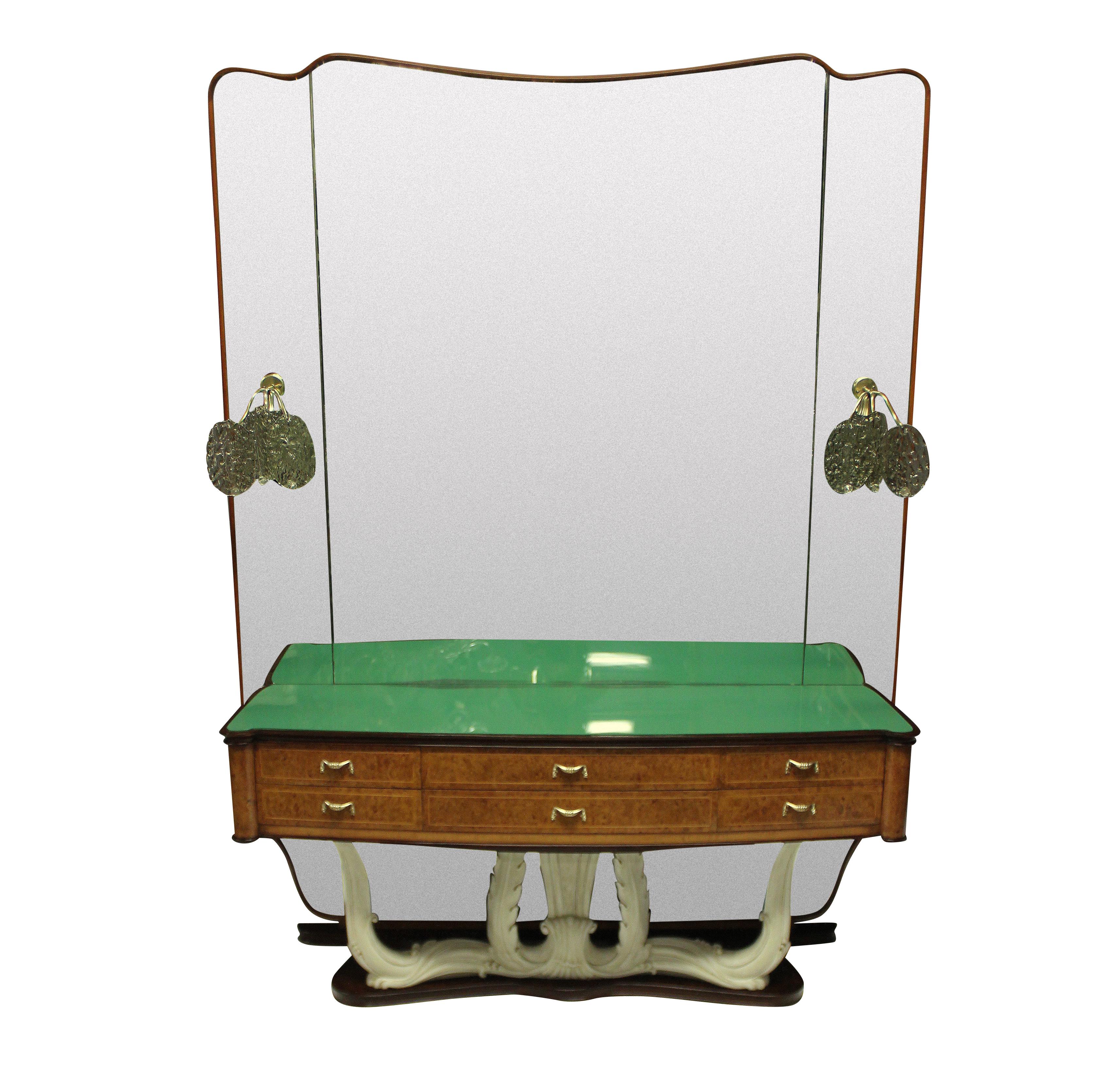 A stylish Italian Mid-Century hall console with full length mirror with sconces. The console with six drawers in walnut root, with brass handles, a carved faux ivory base and its original green glass inset top. The mirror is framed in walnut and has