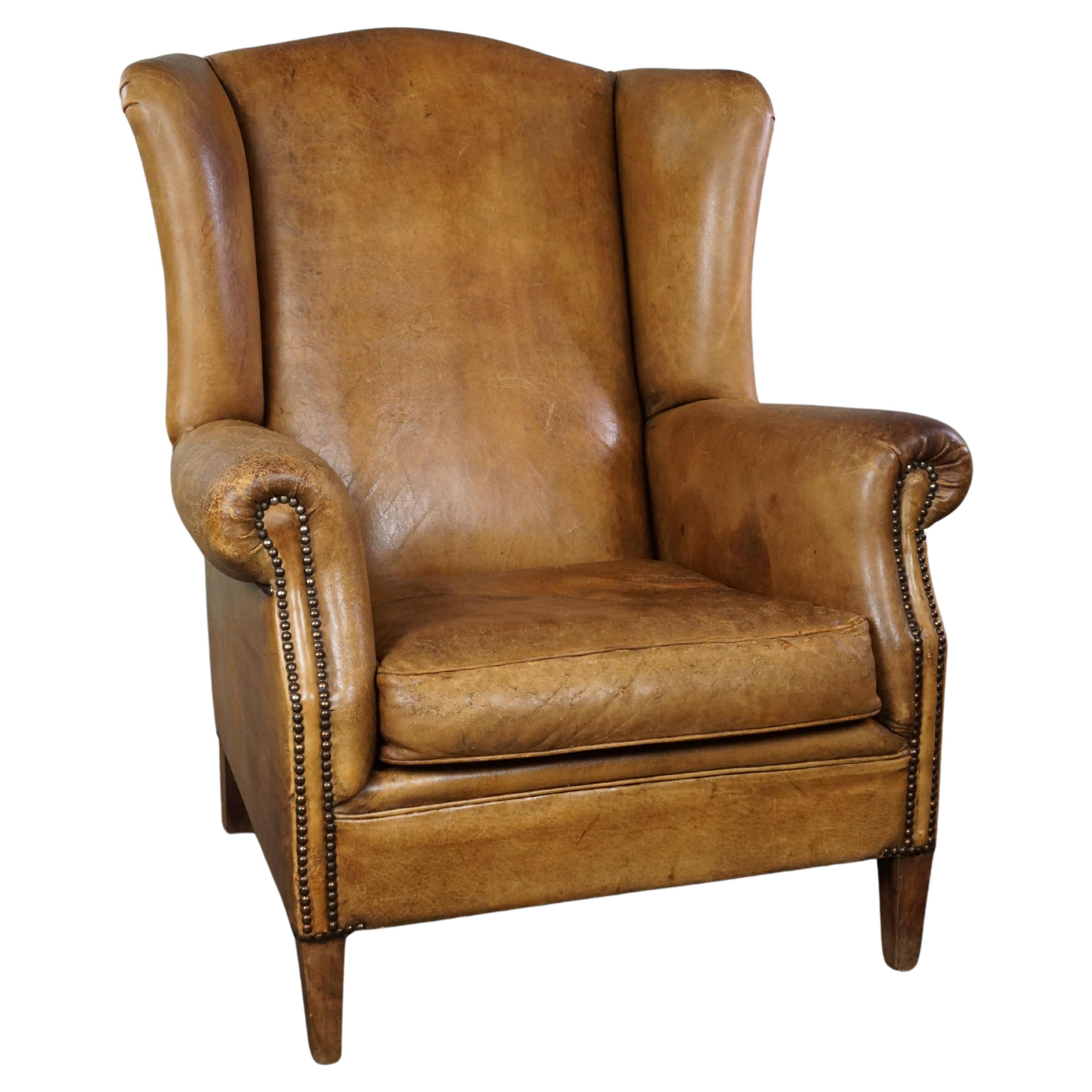 Stylish, lived-in light-colored sheepskin wingback chair For Sale