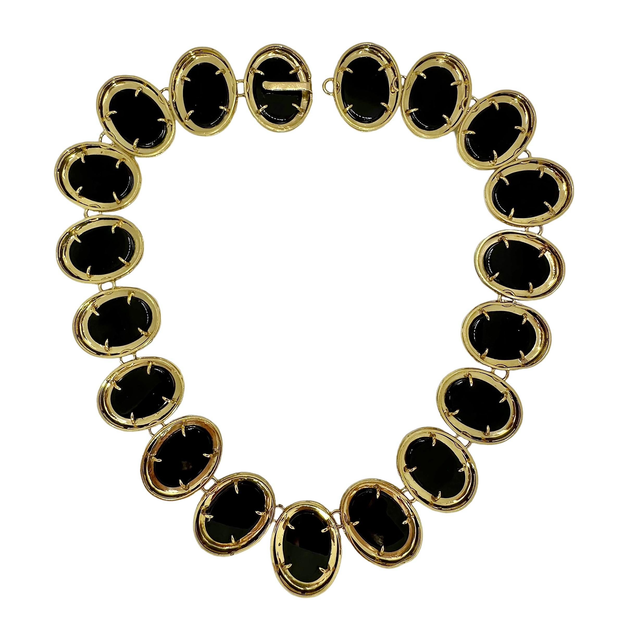 This striking Mid-20th Century 18K yellow gold choker length necklace is comprised of nineteen oval shaped links. Each link is set with one large onyx cabochon surrounded by a high polish finish 18K gold bezel. A  cleverly hidden hook clasp secures