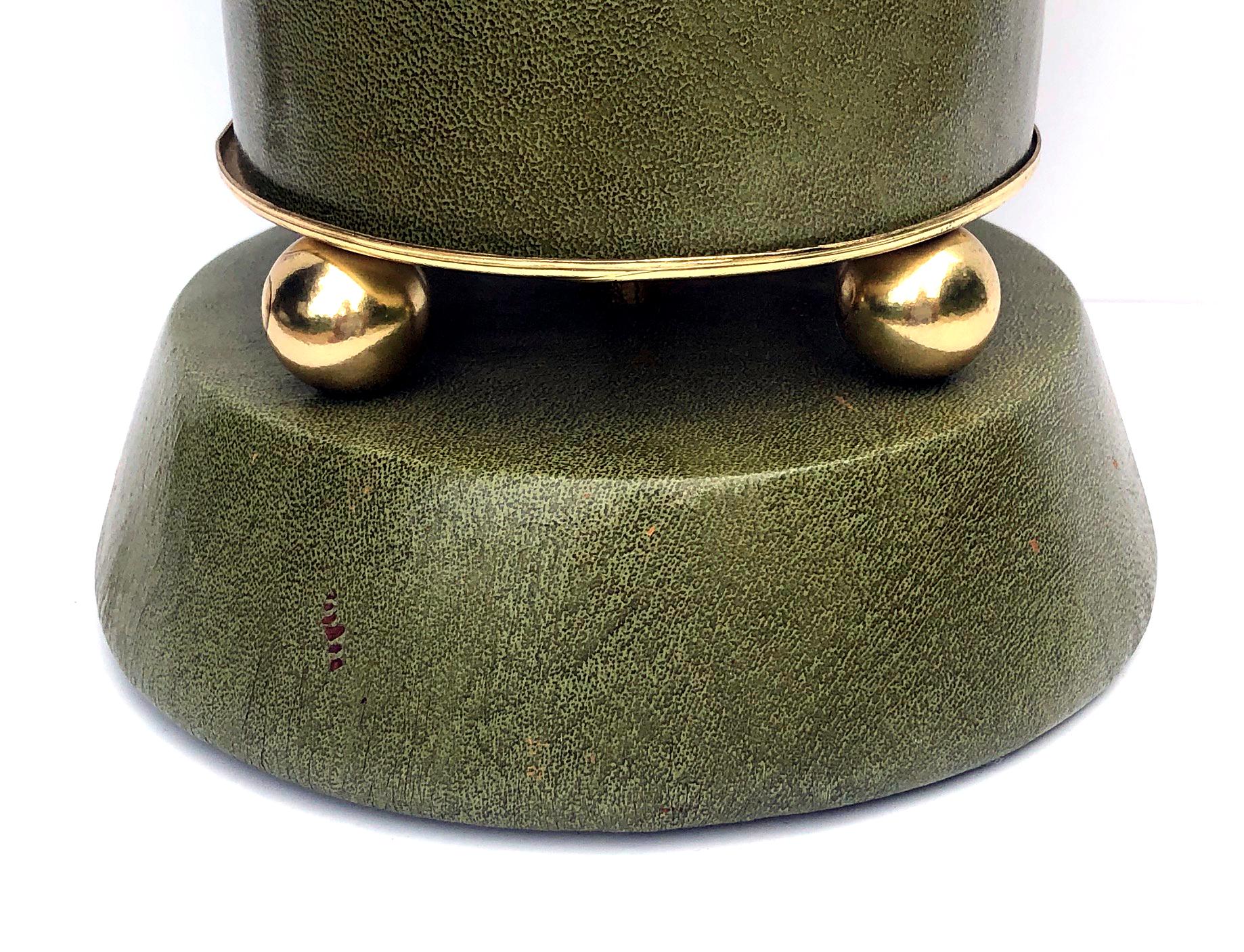 each of cylindrical form covered in a pale green leather fitted with brass spheres all over a canted base.