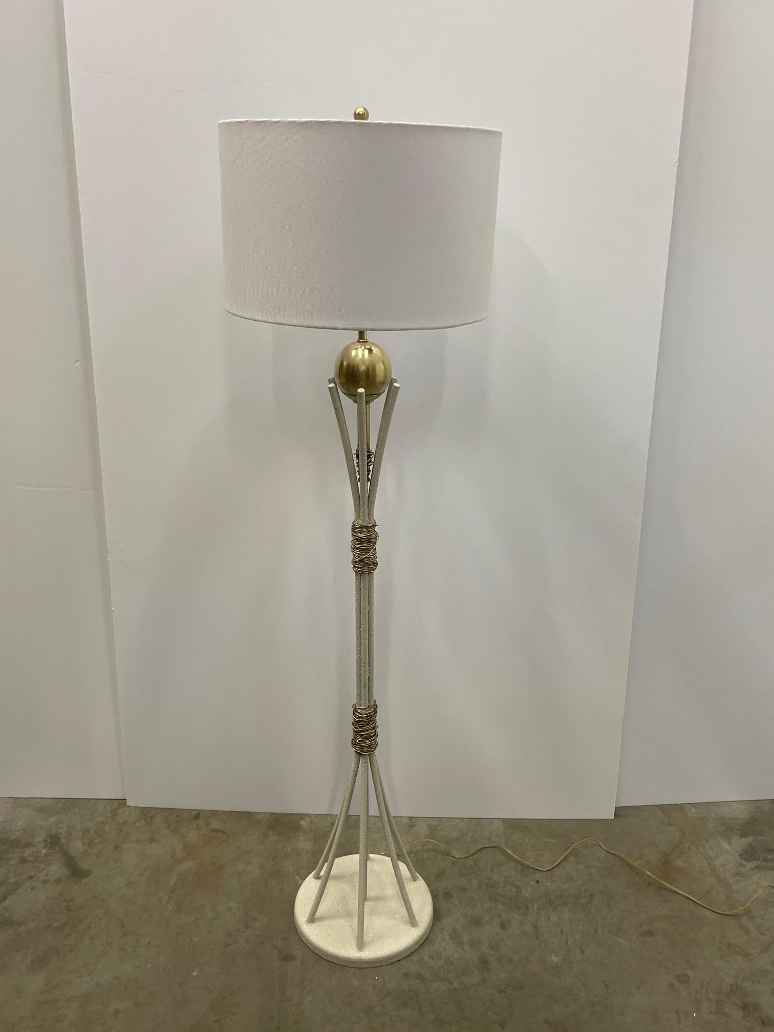 A marvelously designed Mid-Century Modern cream colored floor lamp having textured finish with rods that open at the top and bottom, decorated with brass wire on the column and balancing a large brass ball at the top. Shade not included.