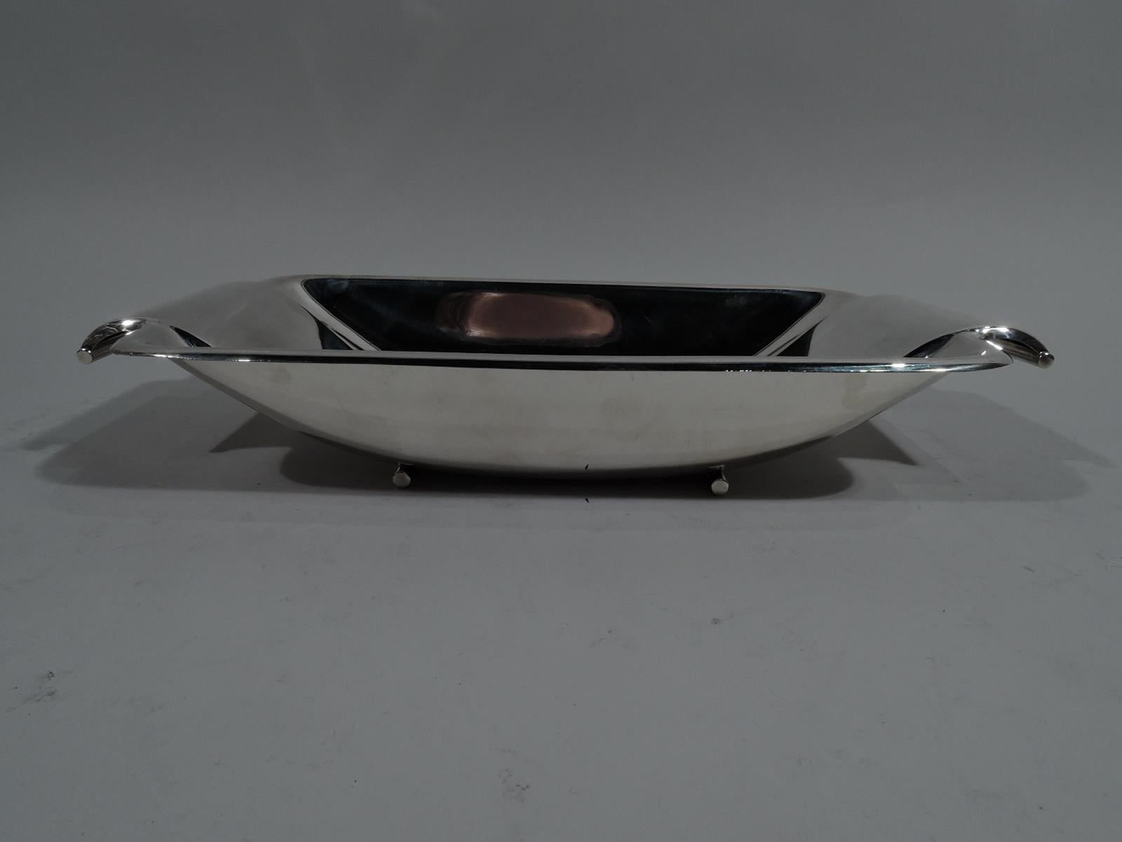 Stylish Mid-Century Modern sterling silver bowl. Made by Reed & Barton in Taunton, Mass. Rectilinear with curved corners and curved and tapering well. Curved and inset end handles terminating in tubes. Rests on two tubular supports. Fully marked and