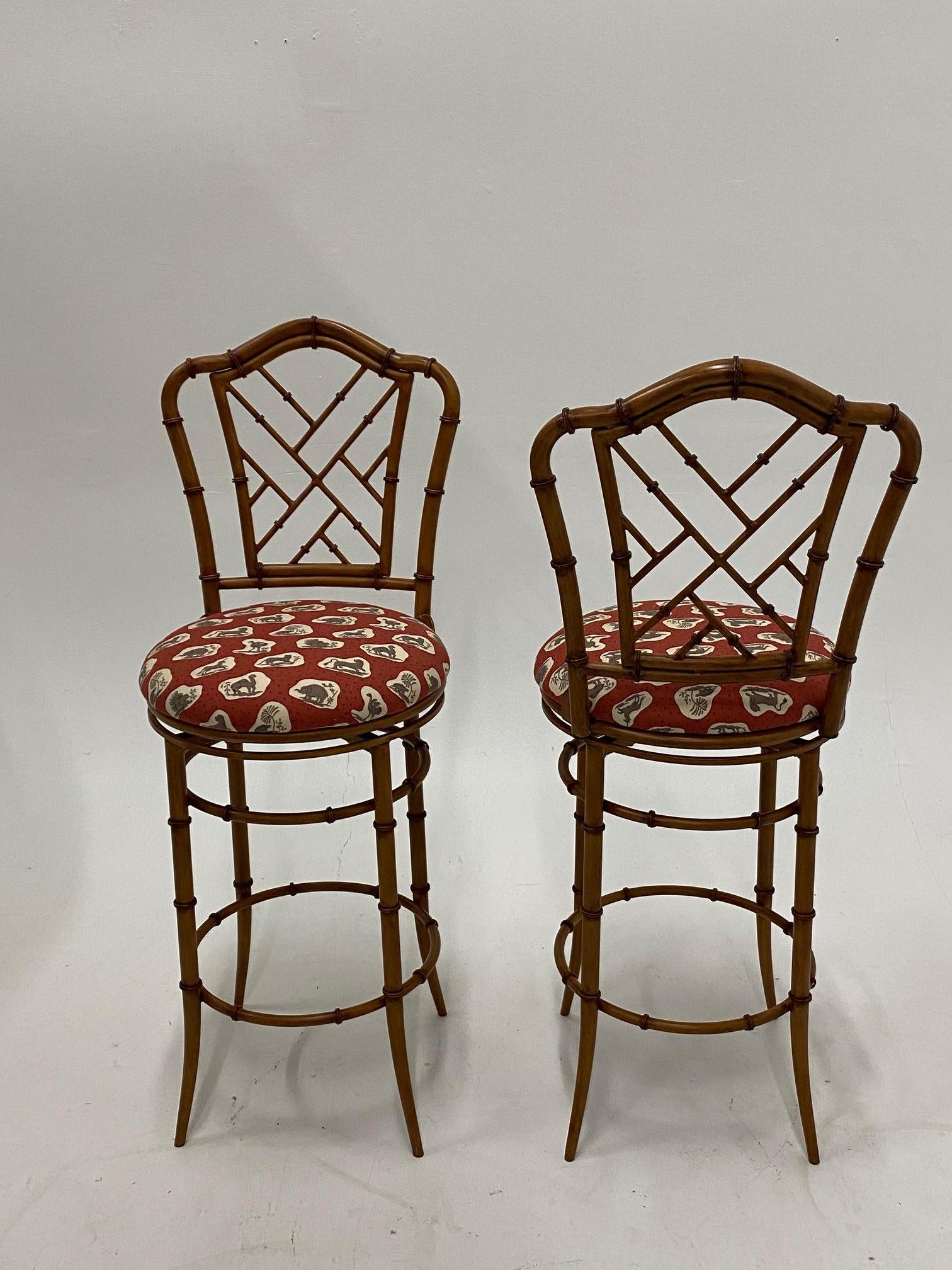 Handsome pair of faux bamboo counter stools made of cast steel with painted enamel finish and having upholstered swivel seats.