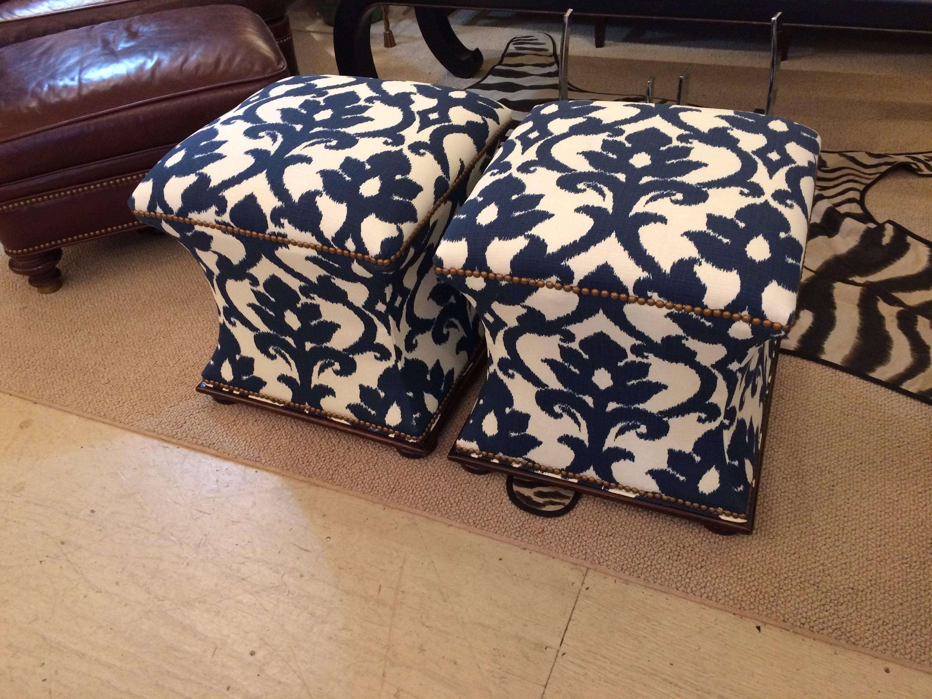 Beautiful pair of vintage Hickory Chair hourglass shaped ottomans with mahogany bases and ball feet. Newly upholstered in a navy and white Ikat designer fabric and French brass nailhead trim.