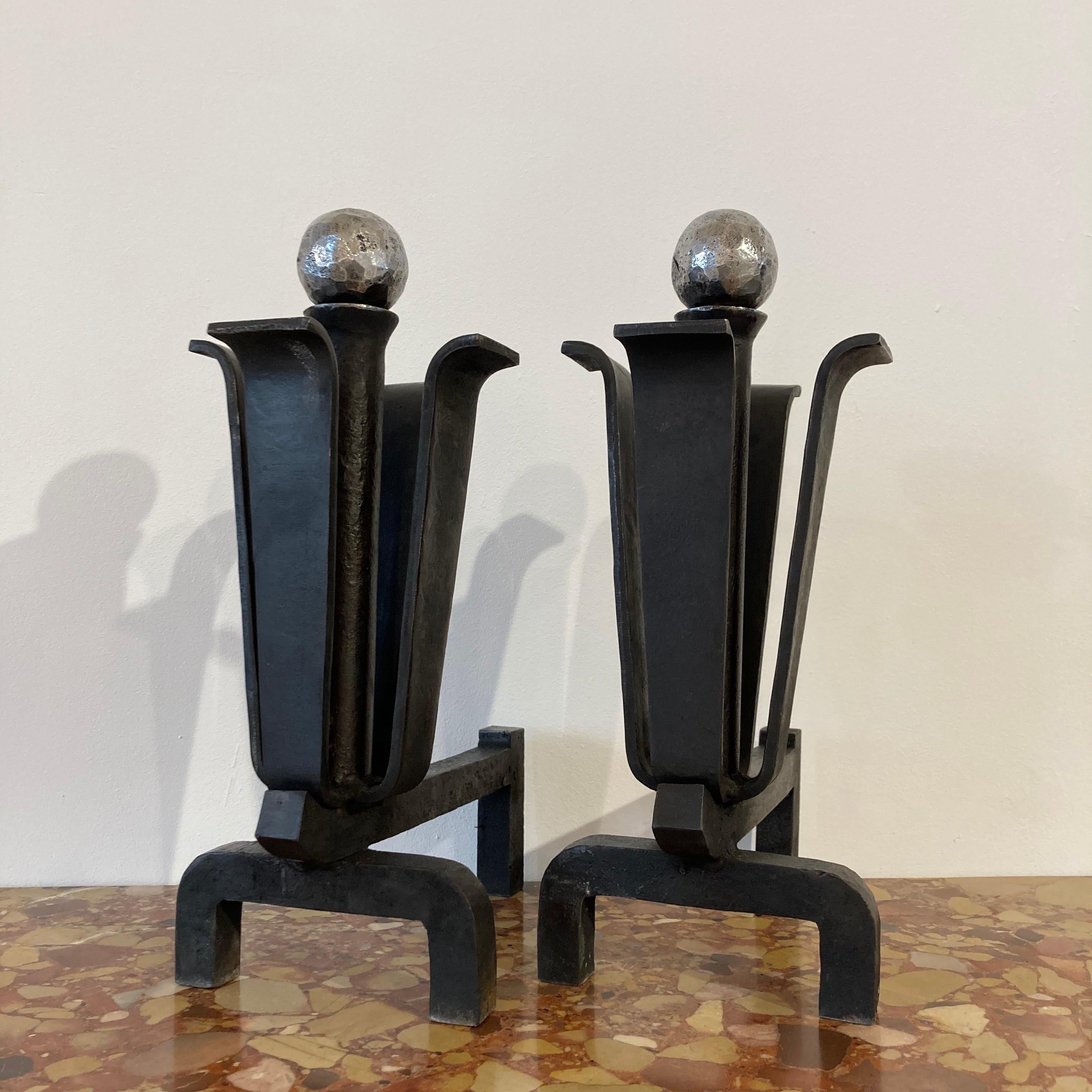 Lovely pair of Mid-Century Modern andirons.
Inspired by an opening flower, these heavy wrought iron andirons open up to reveal a polished hand hammered 