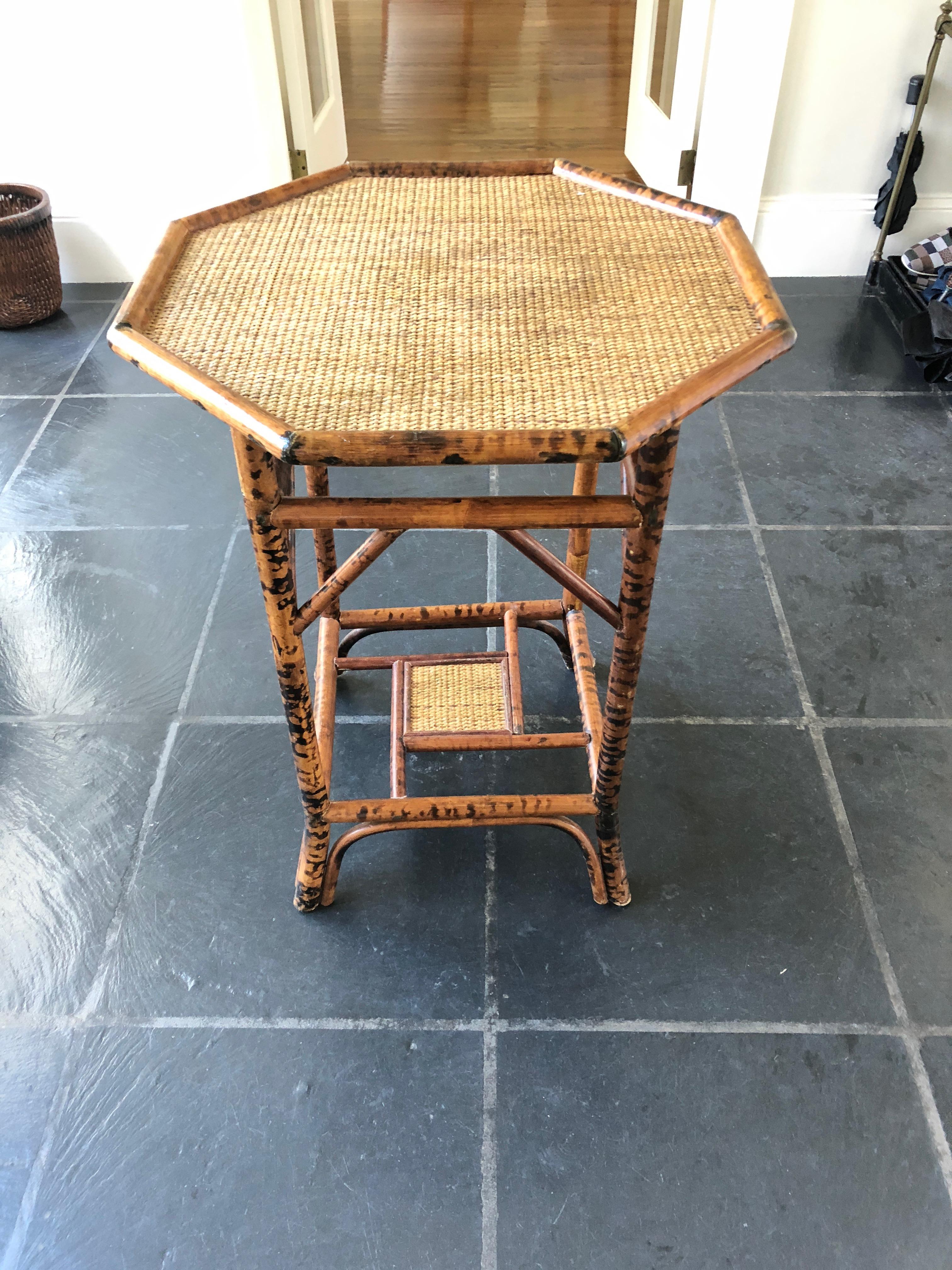 A stylish pair of honey colored and black bamboo and rattan side tables having octagonal tops, elegant legs that splay out at the feet, and a handsome central square in the geometric lower tier.