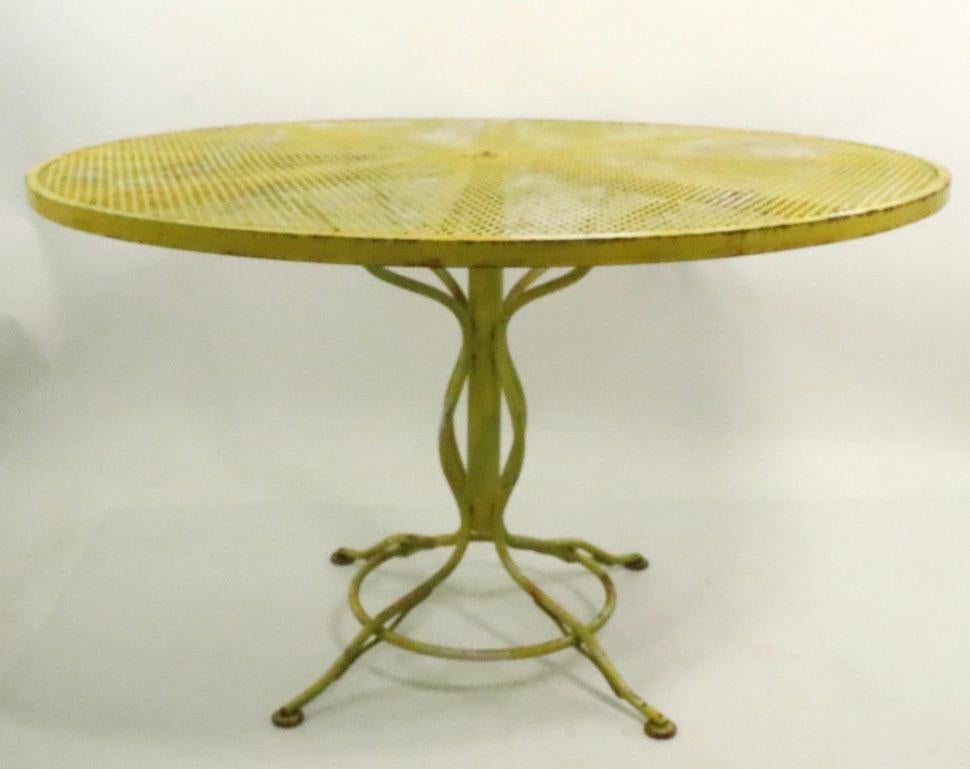 Stylish wrought iron and metal mesh dining table suitable for garden, patio, sunroom, or poolside use. Structurally sound and sturdy, currently in later yellow paint which shows cosmetic wear, normal and consistent with age. Usable as is or we can