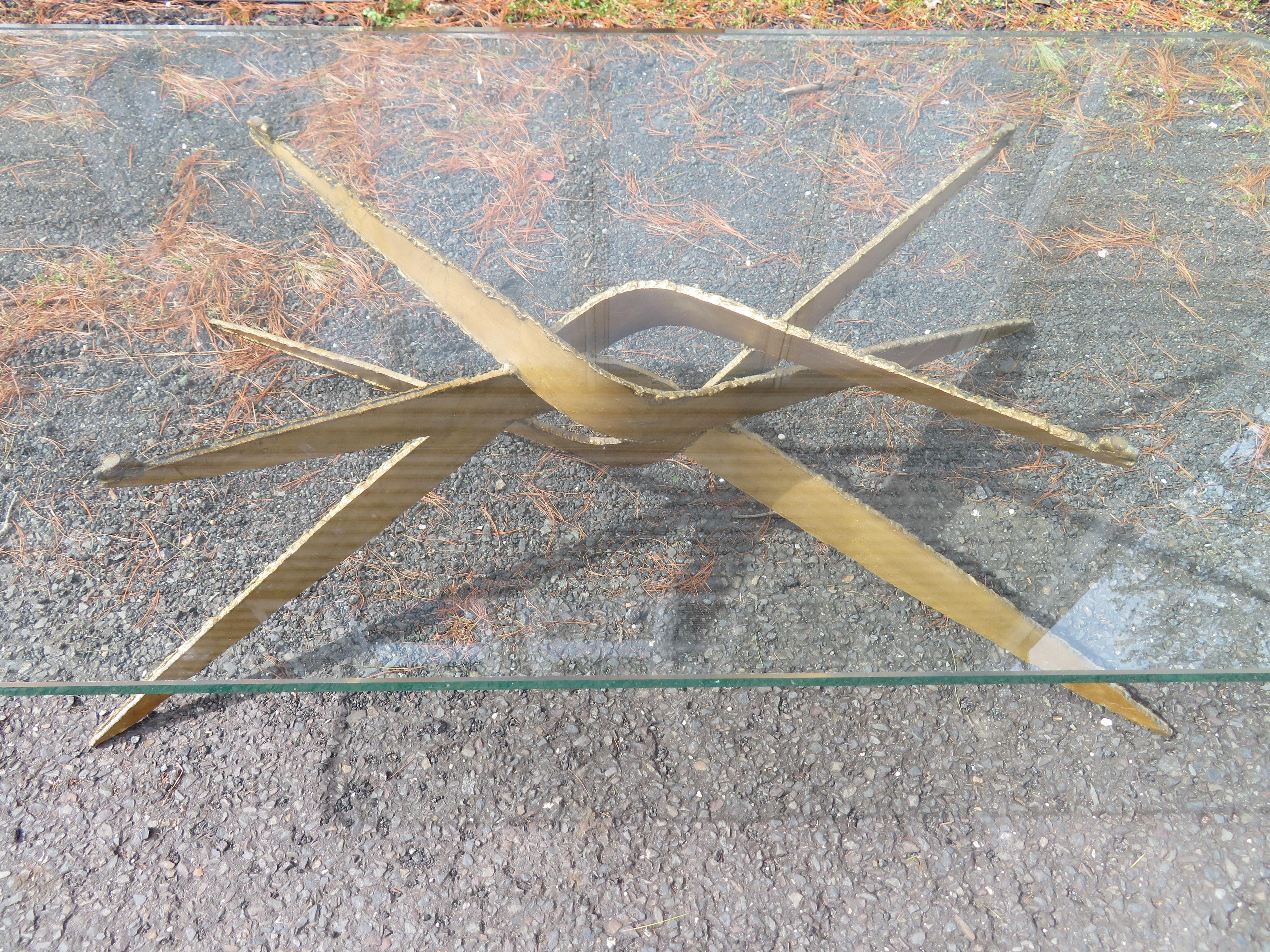 This is an amazing Brutalist glass top coffee or cocktail table of torch-cut steel with a gold base in the style of Silas Seandel. This table measures 16