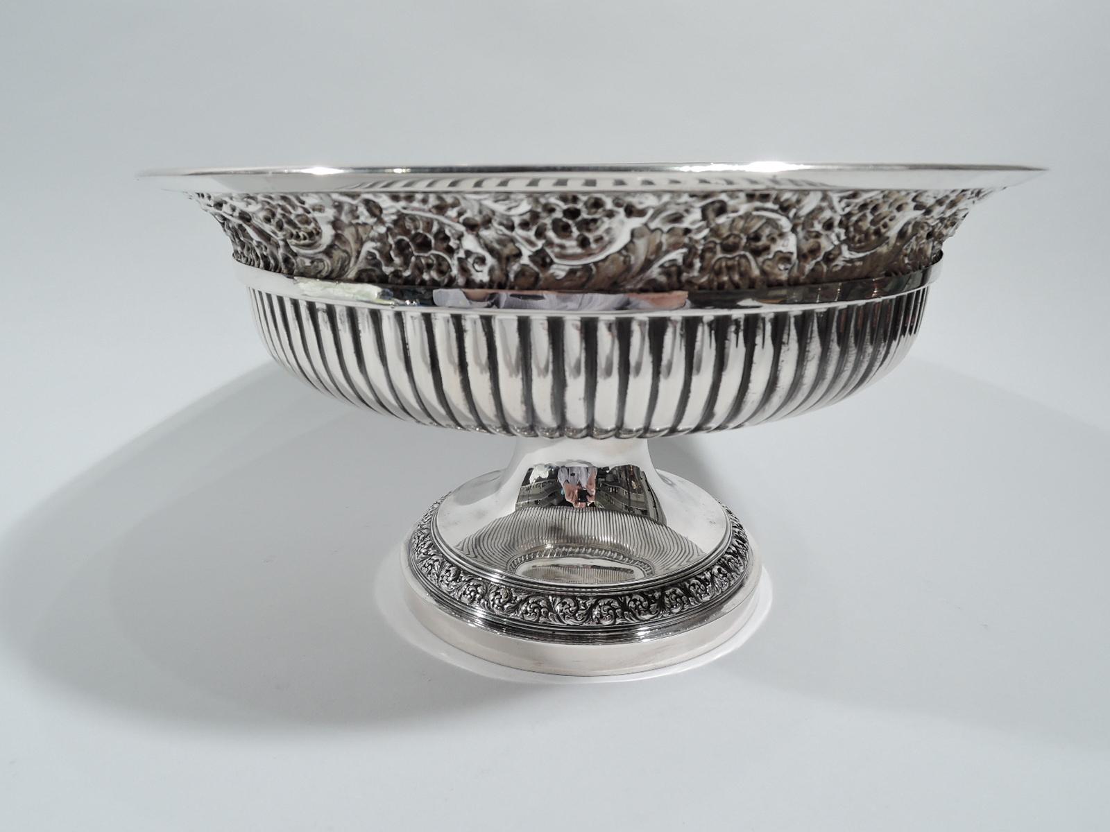 Stylish sterling silver centerpiece compote. Made by Tiffany & Co. in New York, ca 1882. Round bowl; well flat with central circular frame (vacant) radiating flutes. Rim interior and foot have repousse rinceaux borders. Fully marked including