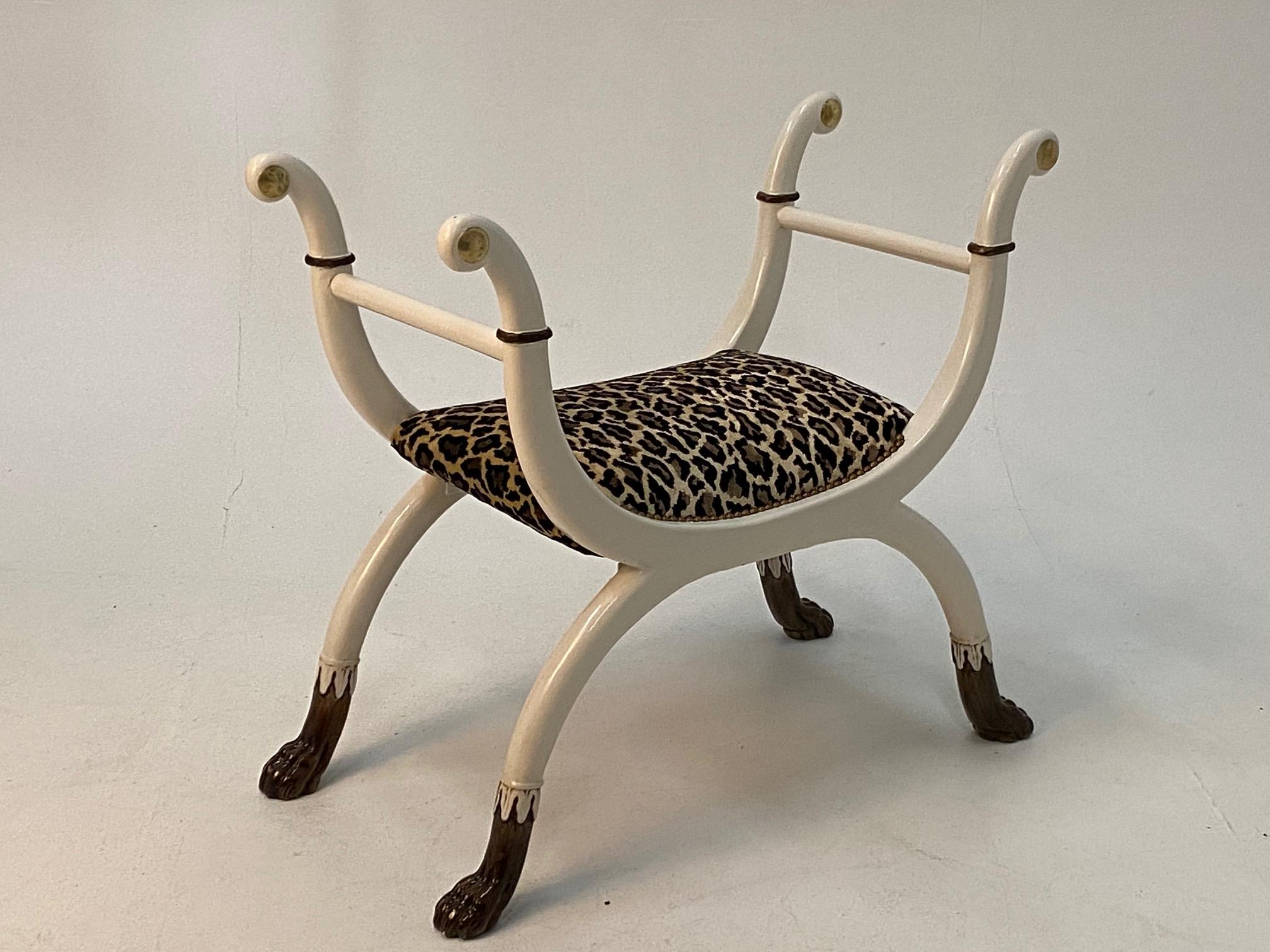 Banco superelegante de estilo Regencia con madera lacada en blanco con detalles en negro y latón y una sensual forma curvilínea. El asiento está recién tapizado en tela de imitación de leopardo complementaria y las patas terminan en unos