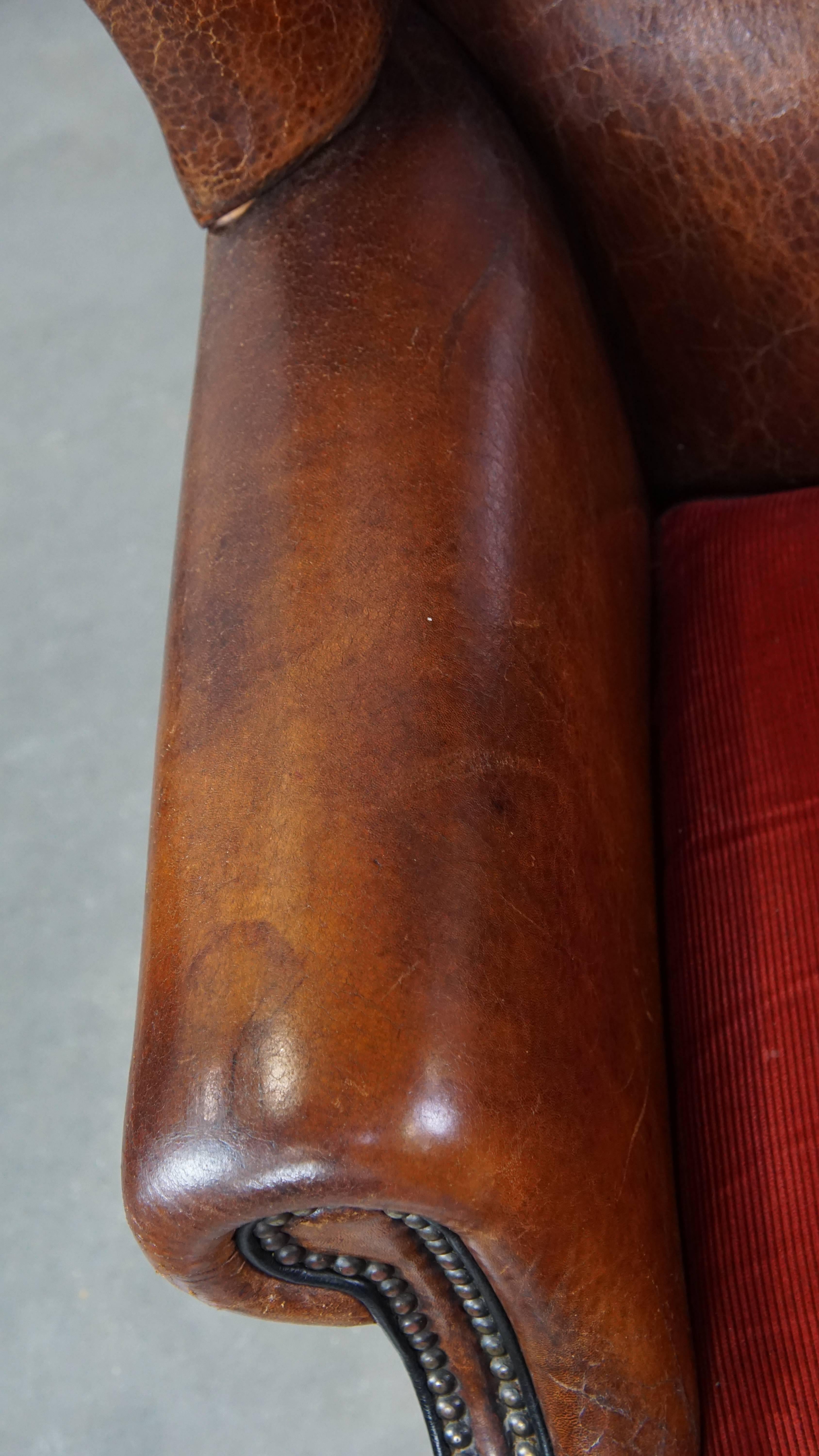 Stylish vintage, luxury sheepskin armchair with a red corduroy seat cushion For Sale 1