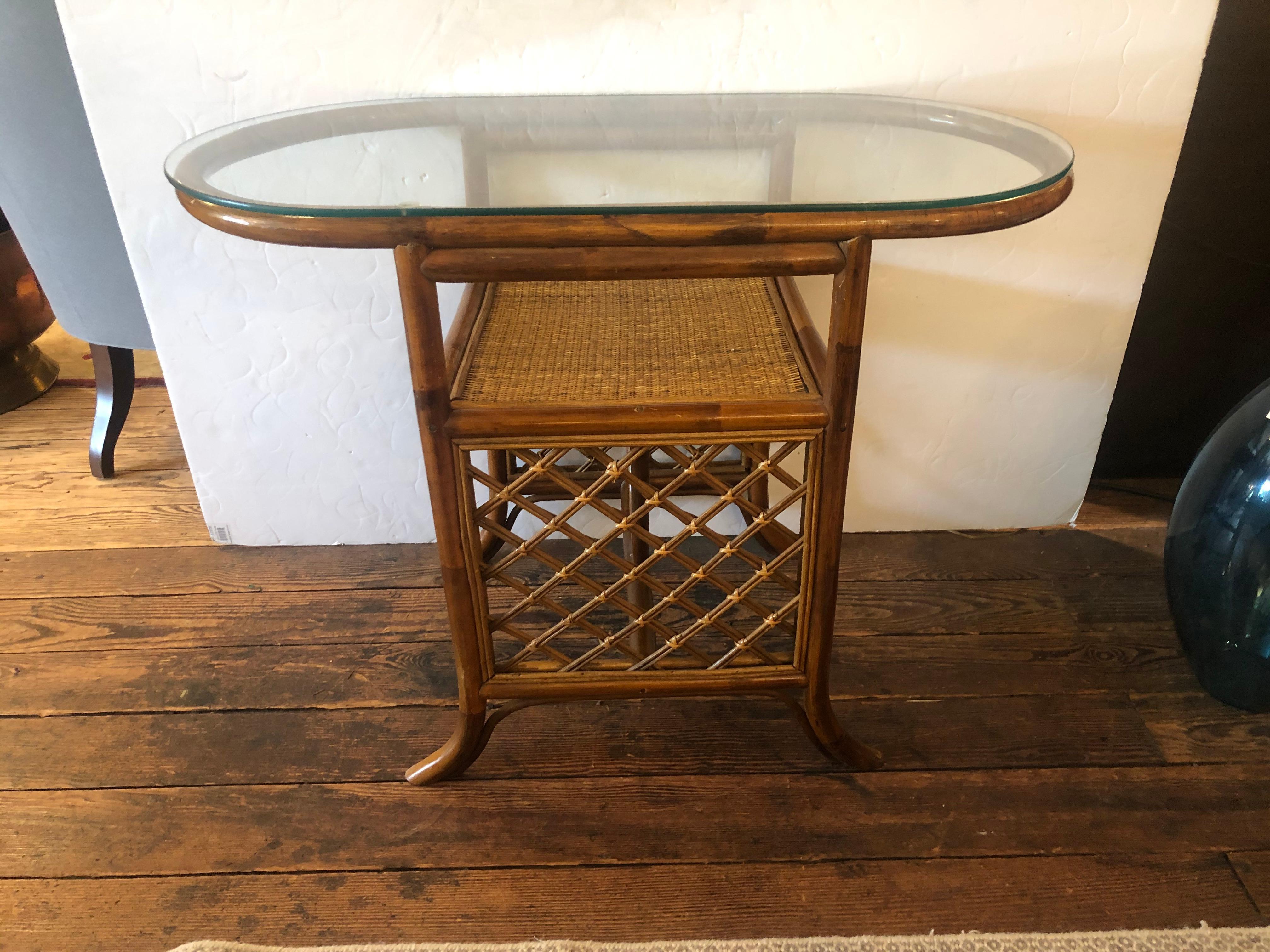 A rare and chic 3 piece rattan and bamboo set including two tier oblong console table and matching diminutive curved side chairs. Each has stylishly splayed legs and handsome hatchwork design. The bottom tier of the console is caned, while the top