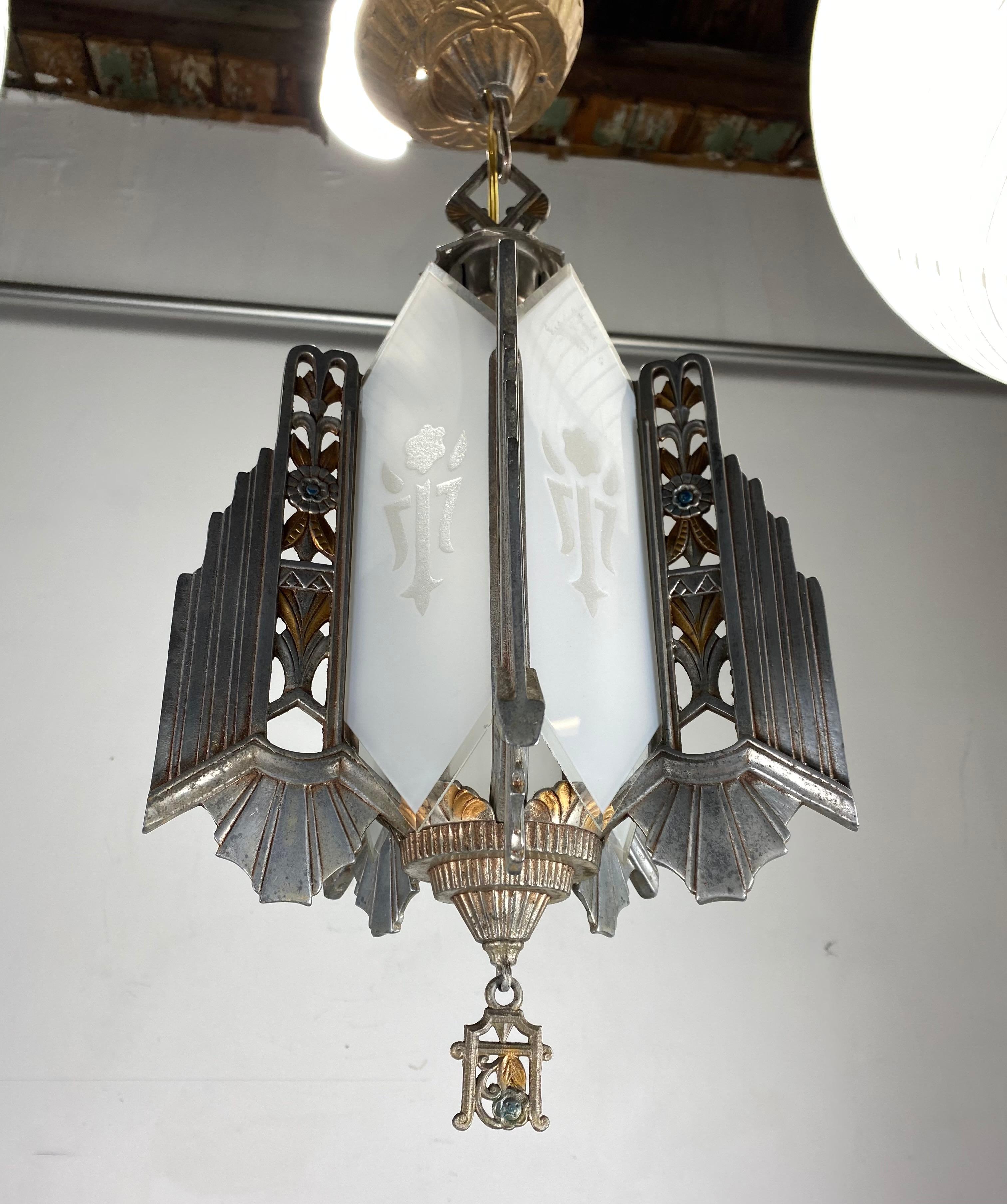 Stylized 1930s metal and glass Art Deco hanging pendant chandelier by Markel, retains original frosted and etched glass panels as well as canopy and finial, wonderful decorative metal work, stunning New York City Deco design.