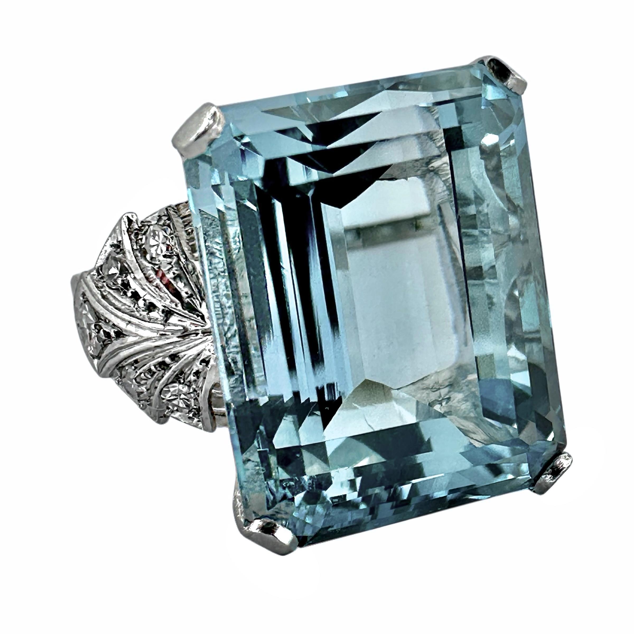 Este llamativo anillo de cóctel de platino, original de la época Art-Deco, está engastado con una aguamarina natural de talla esmeralda en el centro, con un peso aproximado de 20,00 quilates. Su interior está extremadamente limpio y es de un color