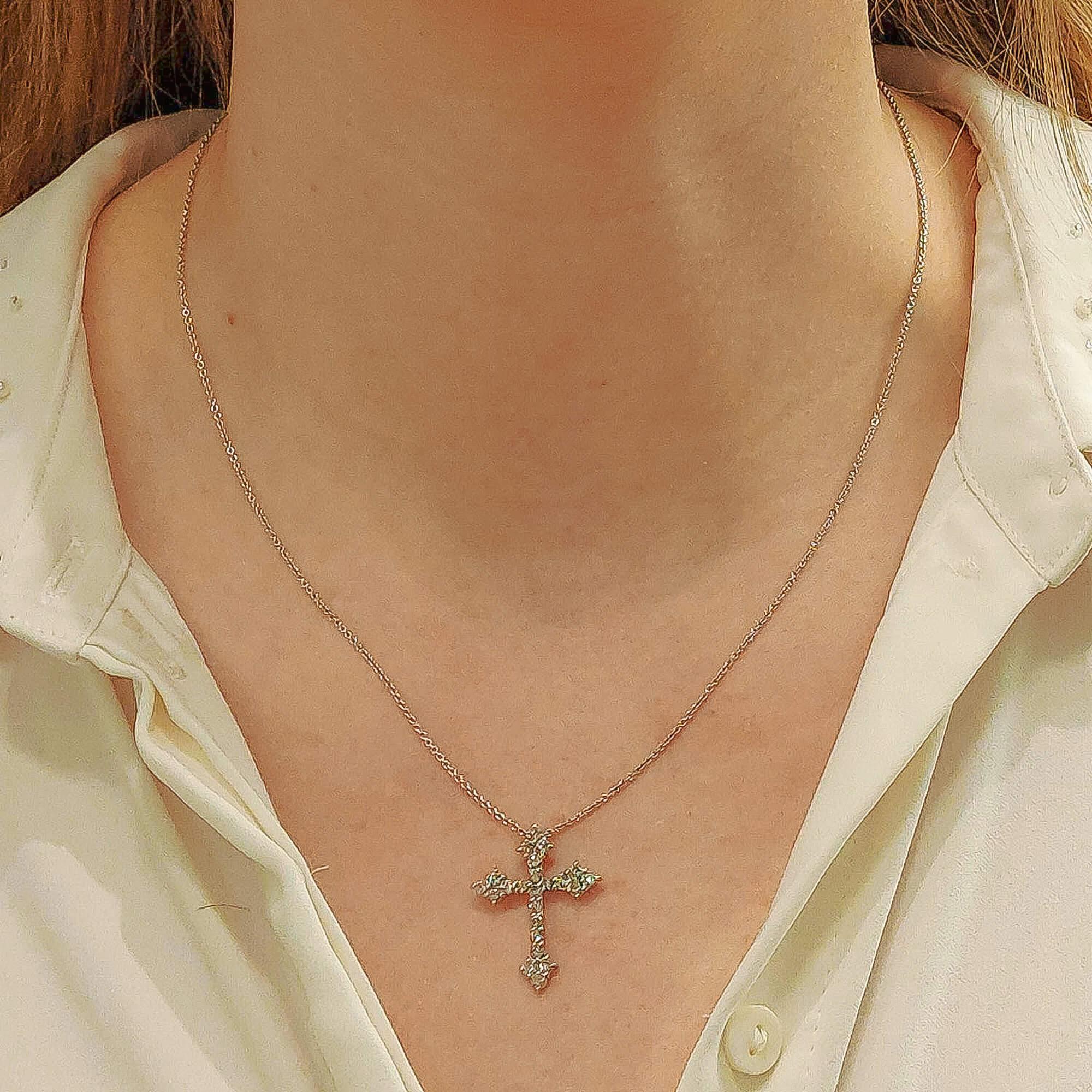 A stylized diamond cross pendant in platinum. 
This pendant is designed as a cross which has a shared-claw-setting throughout with round brilliant-cut diamonds, to an open-back stylized cross pendant fitted to reverse with a fixed bail. 

Diamonds