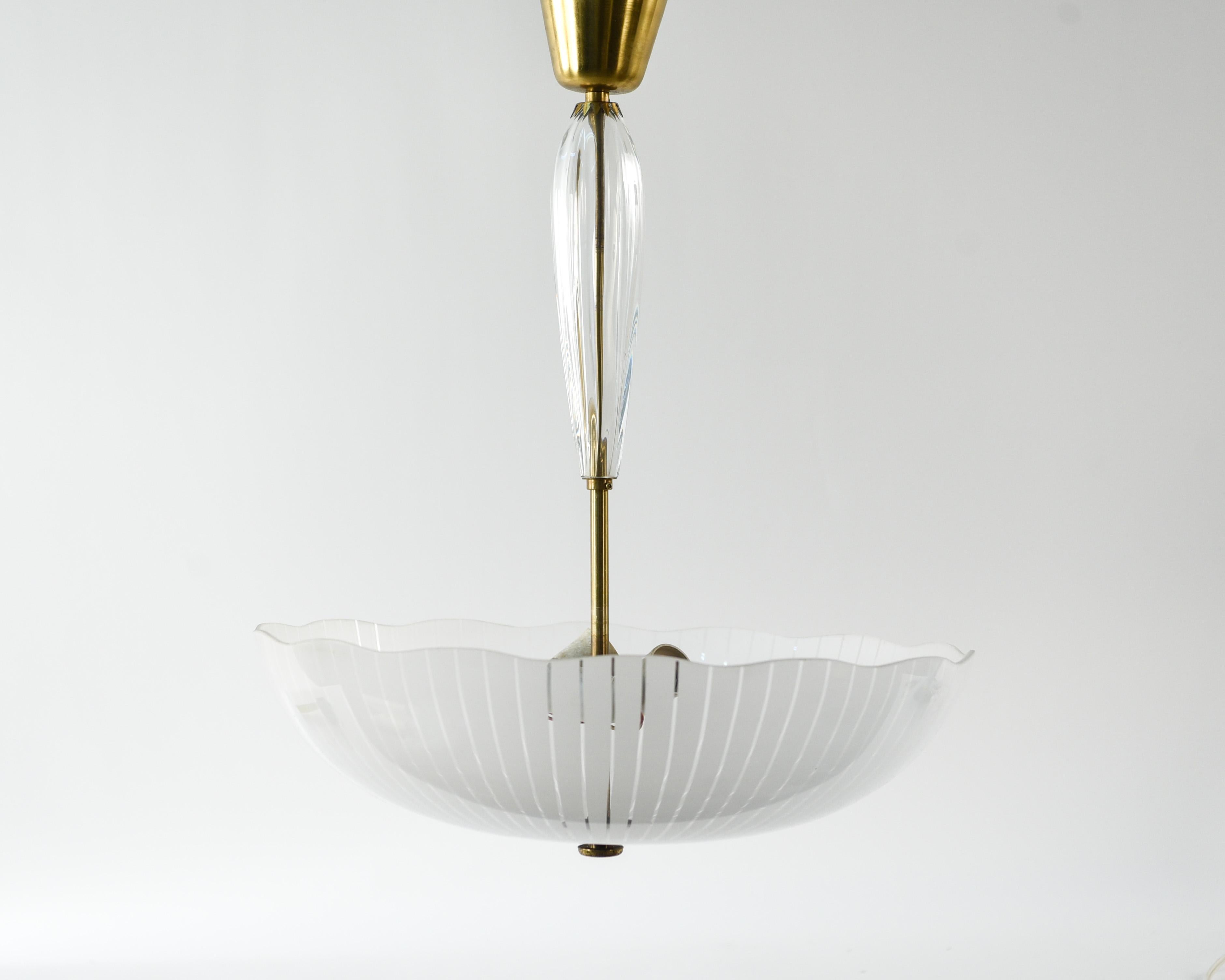 This is a stunning stylized etched glass chandelier with brass hardware by Carl Fagerlund for Orrefors, circa 1940s. This rare piece has a timeless elegance to it.