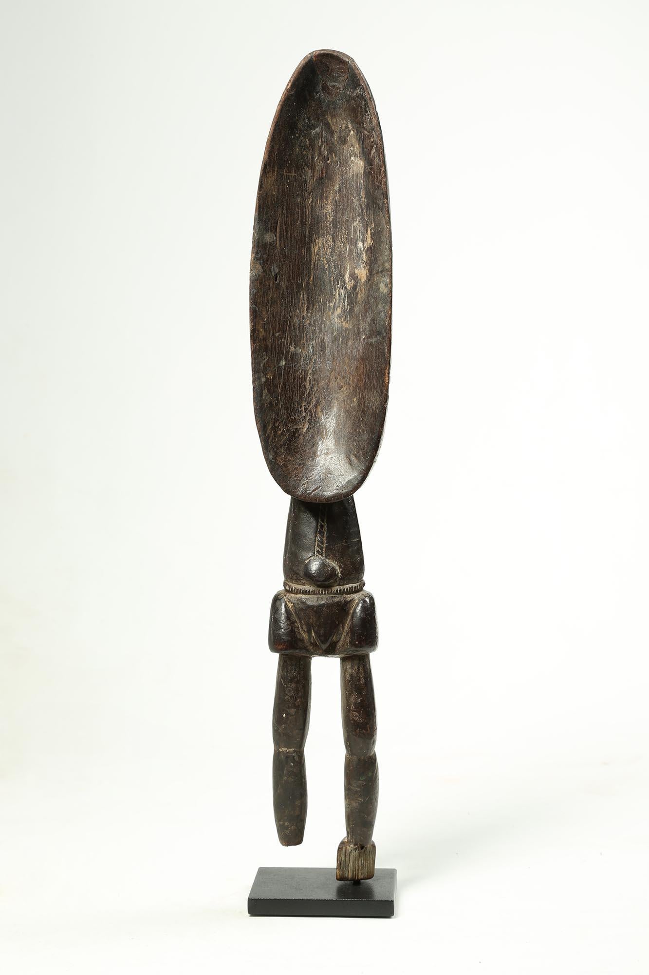 Large, stylized human wood serving spoon from the Dan People, Ivory Coast, Africa. Standing human figure with spoon bowl representing the upper body and head, with two legs, note that the feet are broken and worn from use. Pronounced navel and