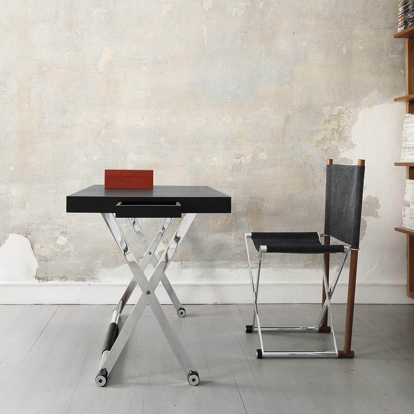 Designed with a modern interior in mind, this luxury desk is foldable and can be a precious and versatile addition to any room. The top in solid wood is covered with frosted black leather, while the four crossing legs are in aluminum, with a leather