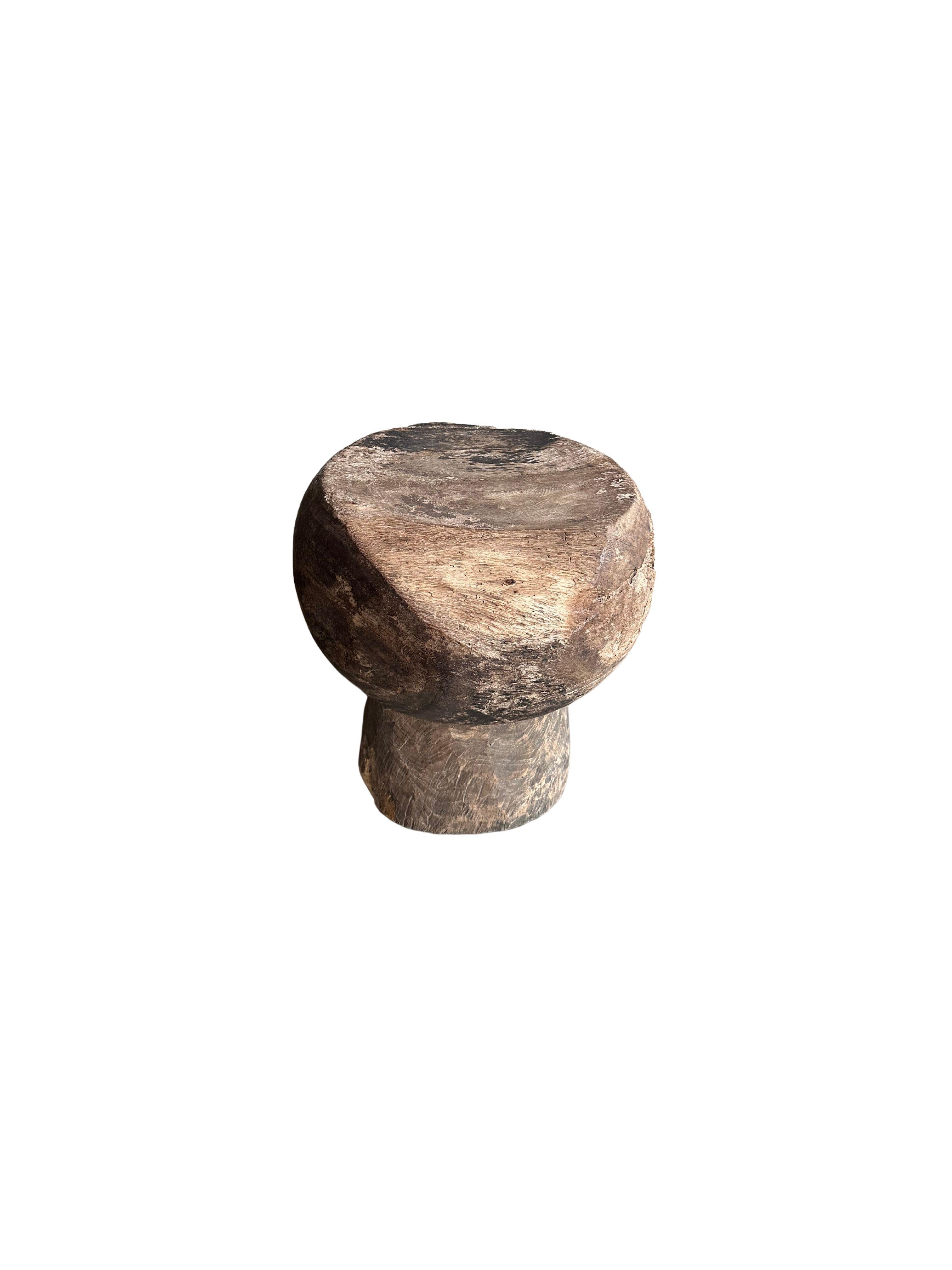 A wonderful Javanese Suar wood stool featuring an array of wood textures and shades. The subtly curved seat adds to its charm. This item features an age related patina that has developed on the wood. A sculptural object perfect to bring warmth to