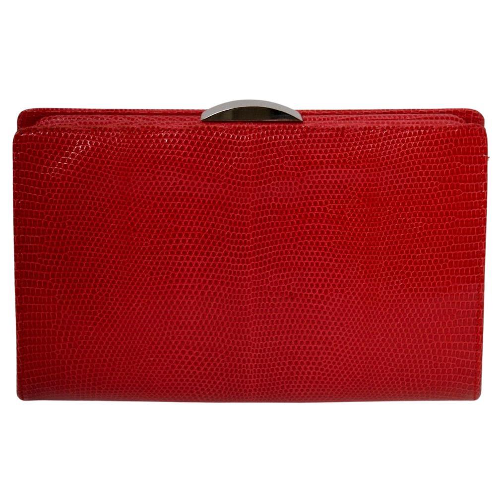 Perfect clutch in cherry red lizard by Suarez, known for their exotic skin handbags, features an interesting metal and black bead chain that converts it into a shoulder bag. The shiny silver metal clasp is the only exterior adornment to the clean,