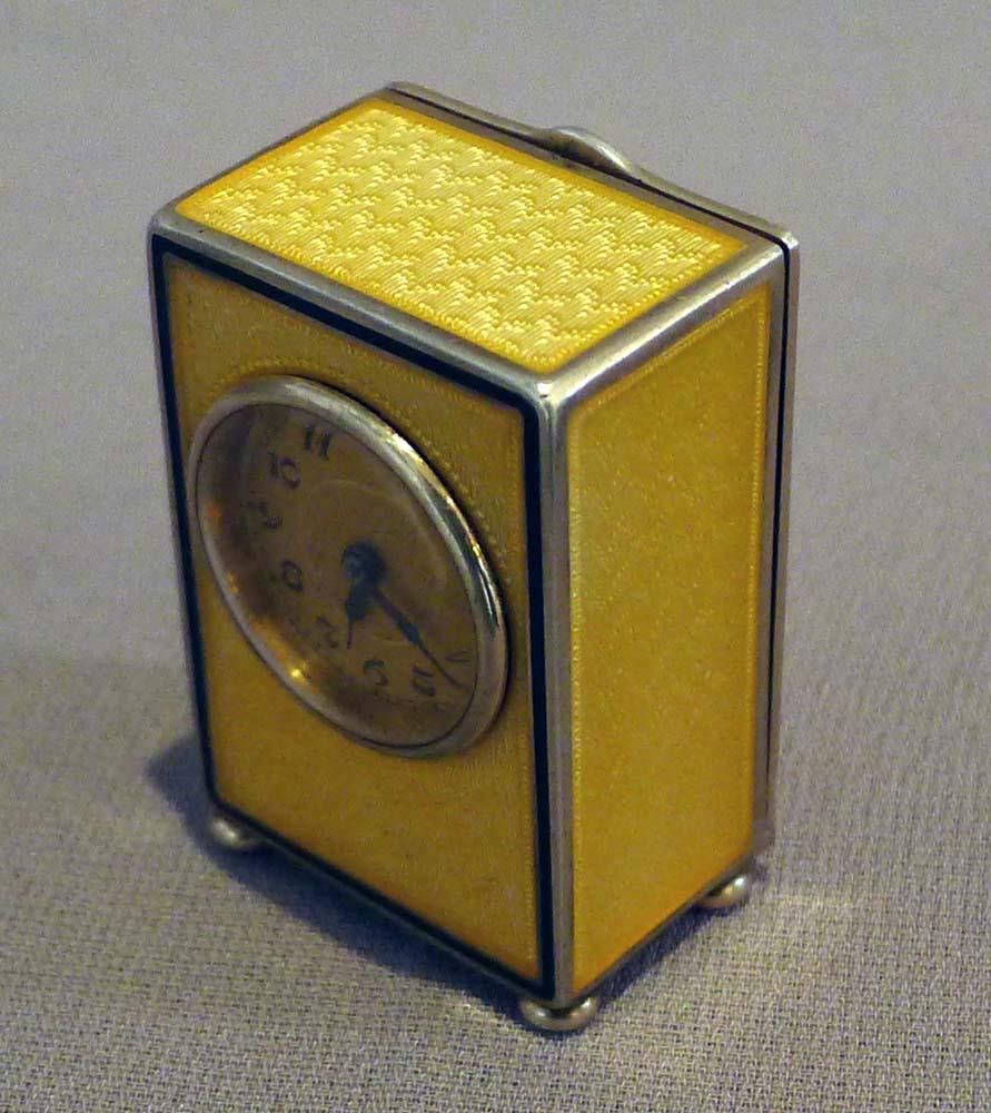 An exquisite sub miniature carriage clock in mint condition.
The lemon yellow guilloche enamel decoration to front sides and top is in perfect and unmarked condition. To the front the enamel is bordered by a line of black enamel. The circular dial