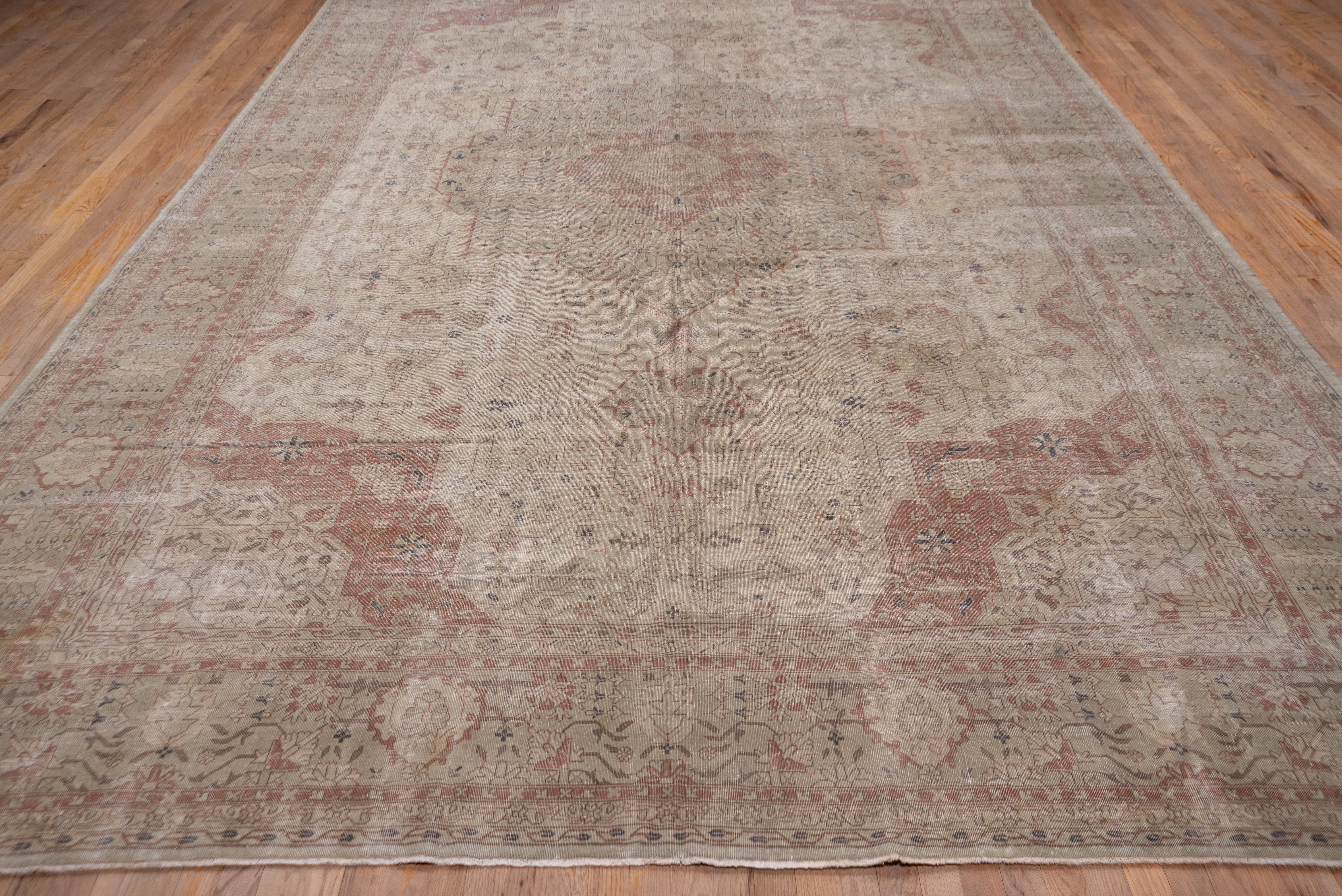 In the Persian Heriz style with a large octogramme medallion and matching quarter corners with angular vines and flowers, all on a cream ground. The khaki border shows a classic in-and-out palmette pattern.