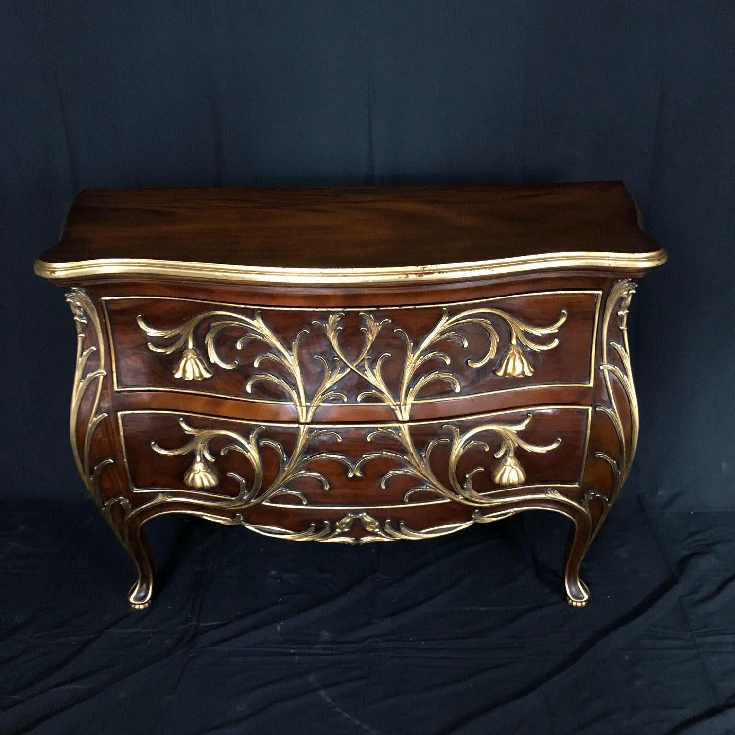 A sublime Louis XV style serpentine walnut gilt trimmed chest of drawers having exquisite gold details that seamlessly extend into four pulls on the two drawers comprised of flowers. A work of art! 

#5174.