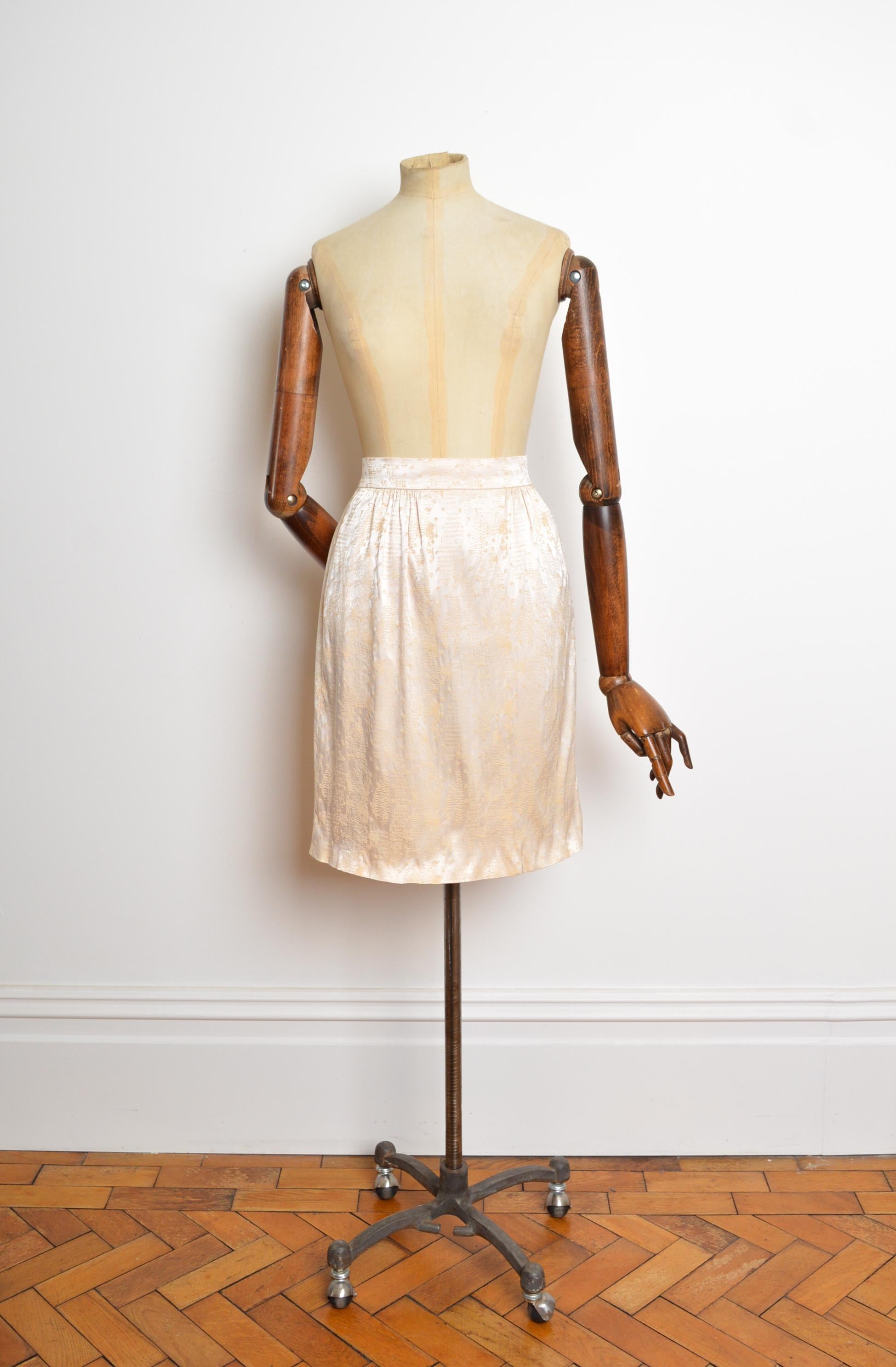 Une opulente jupe en satin Vintage du couturier français MADAME GRÉS. 
Il se compose d'un fascinant jacquard de satin crème texturé, d'une bande de taille haute avec fermeture éclair dissimulée au dos, d'un intérieur entièrement doublé de soie et