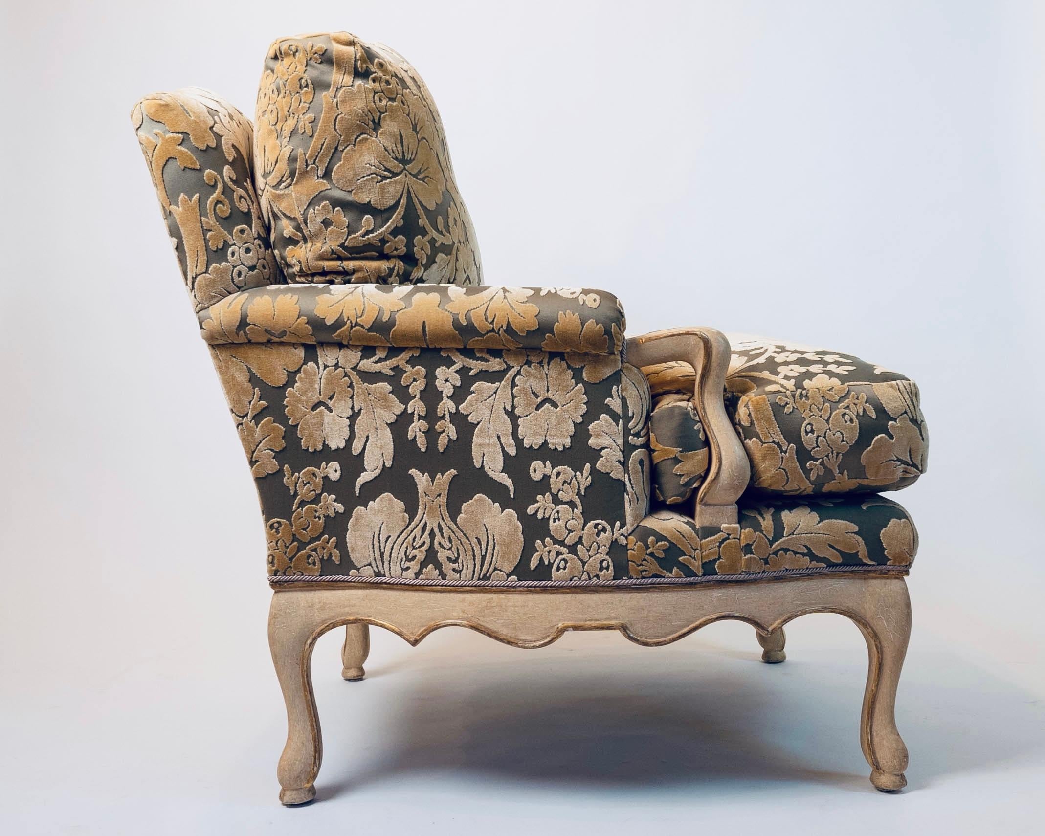 Sumptuous pair of oversized bergere chairs upholstered in a muted gray-green silk with soft gold velvet upholstery. The regal club chairs are in a French Country style by designer F. Robert Scott, having down filled seat cushions and cream painted