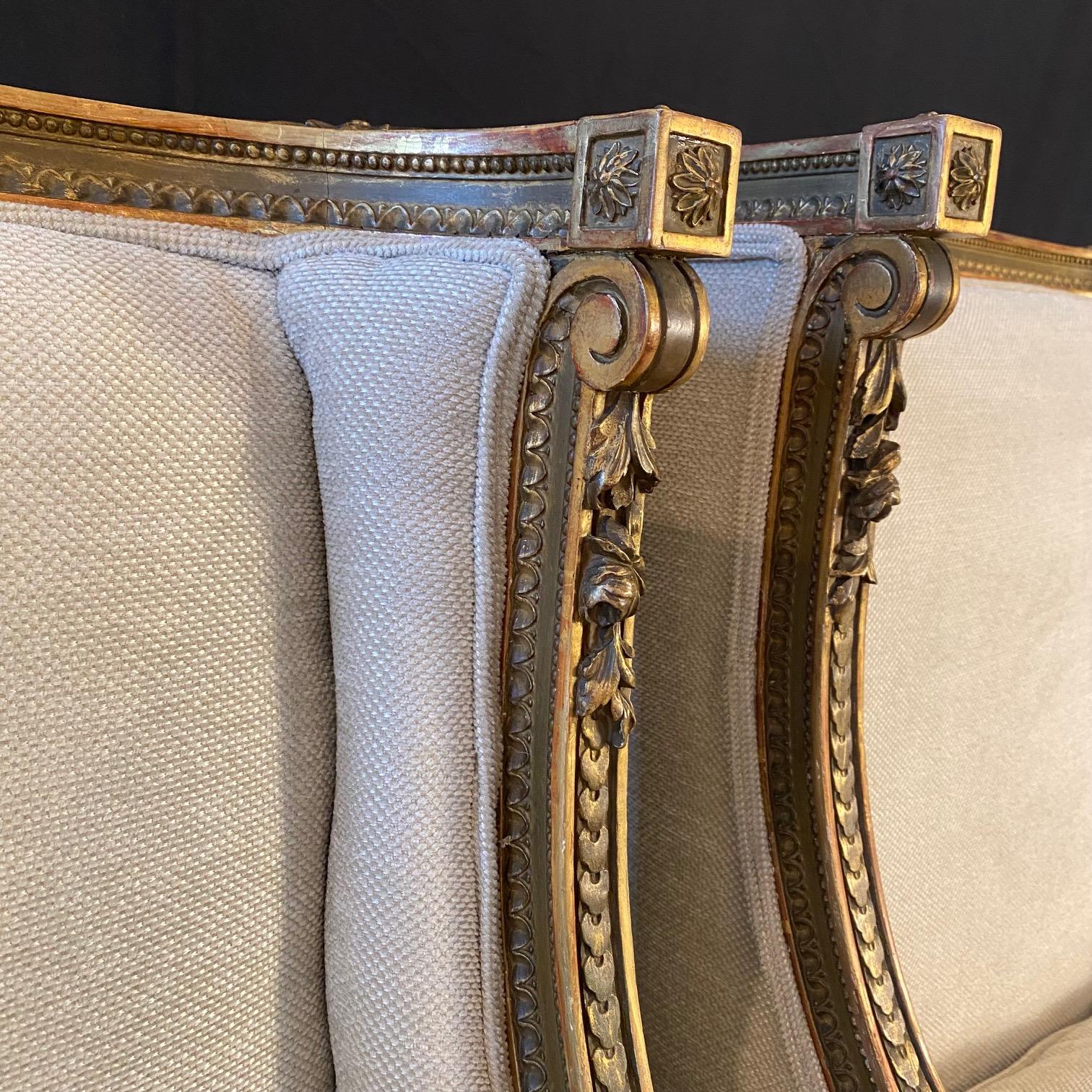 Asombrosa pareja de sillones de salón de estilo neoclásico Luis XVI.  Distintivamente restaurada con tapicería nueva de alta gama en mezcla de lino marfil/beige y toques dorados con textura de chenilla.  Estas sublimes bergeres son  en un estilo
