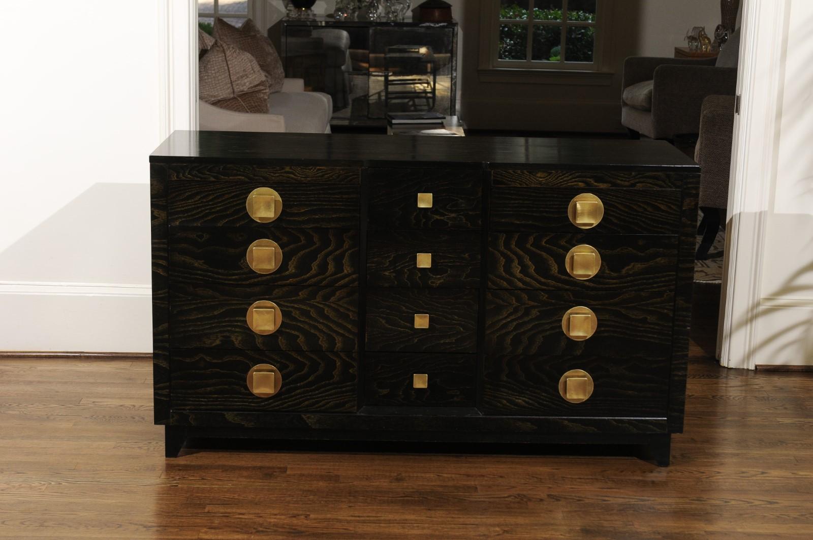 A divine 12-drawer chest by John Stuart, circa 1950. Magnificently crafted case executed in striking cerused oak with fabulous chunky solid brass hardware marking the front. This unusually breathtaking piece is both slick and organic. An incredible