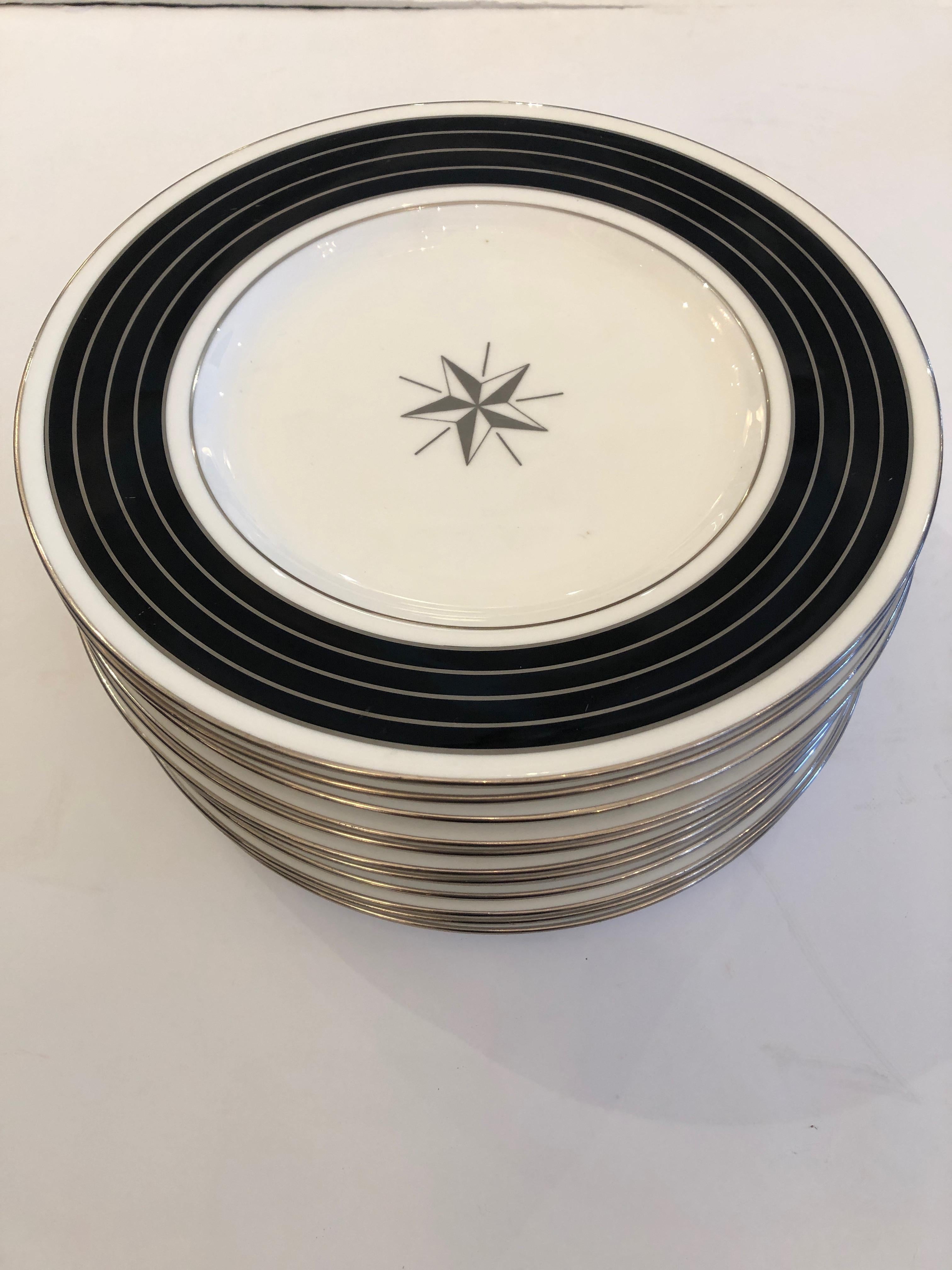 12 handsome Minton china dinner or service plates having contemporary style with black and platinum silver striped borders, white background and a central star decoration.