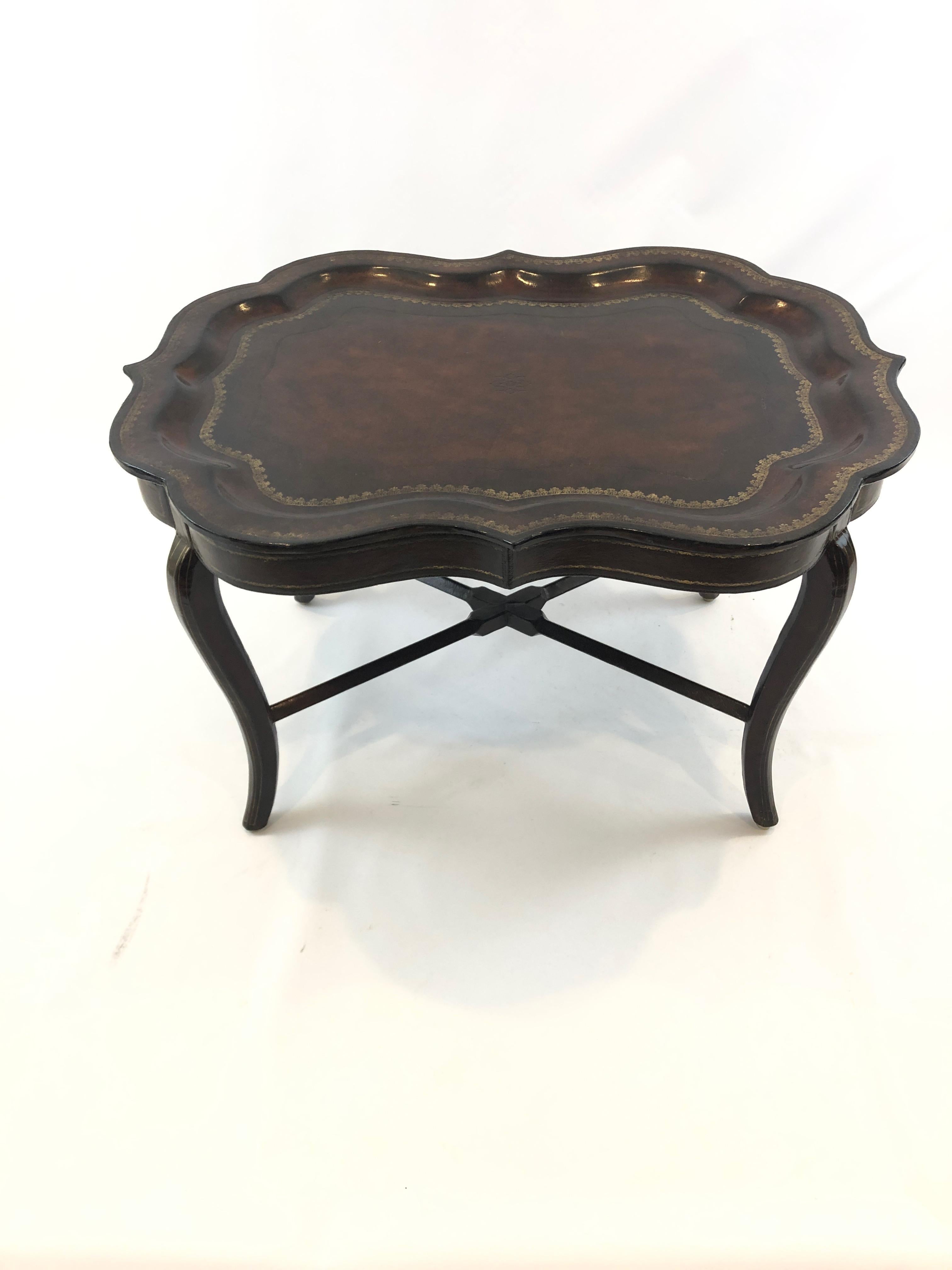 Superb embossed rich brown tooled leather tray coffee table having a scalloped tray removable top with gilded embellishments as well as stunning leather wrapped base.