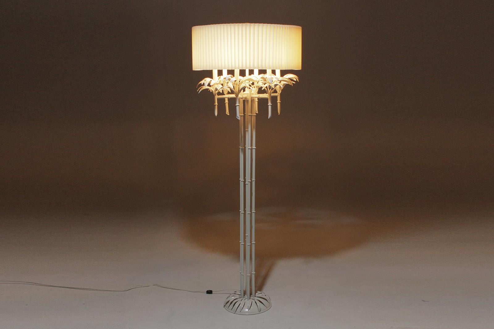 Eine große, sehr dramatische, weiß lackierte Hollywood Regency Stehlampe mit wunderschönen Palmenblättern an den 6 Kandelaberarmen und einer eleganten, mit Blütenblättern bedeckten Bambussäule mit Sockel. Originaler plissierter Acrylschirm.
Bis zu