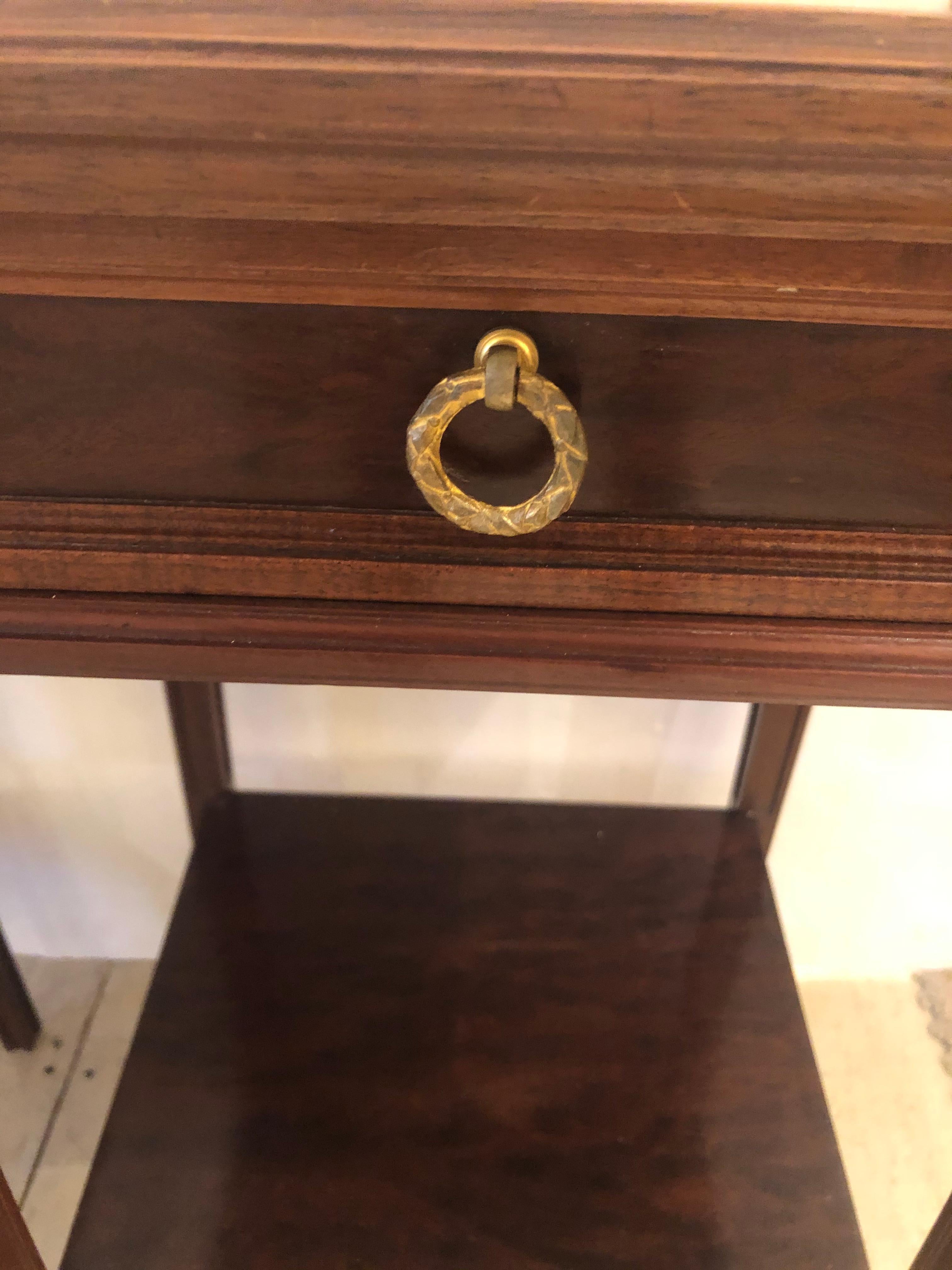 Elegant pair of French 19th century mahogany nightstands or end tables having gorgeous bronze mounts, single dovetailed drawers and inset cream marble tops. There a lower tier 11