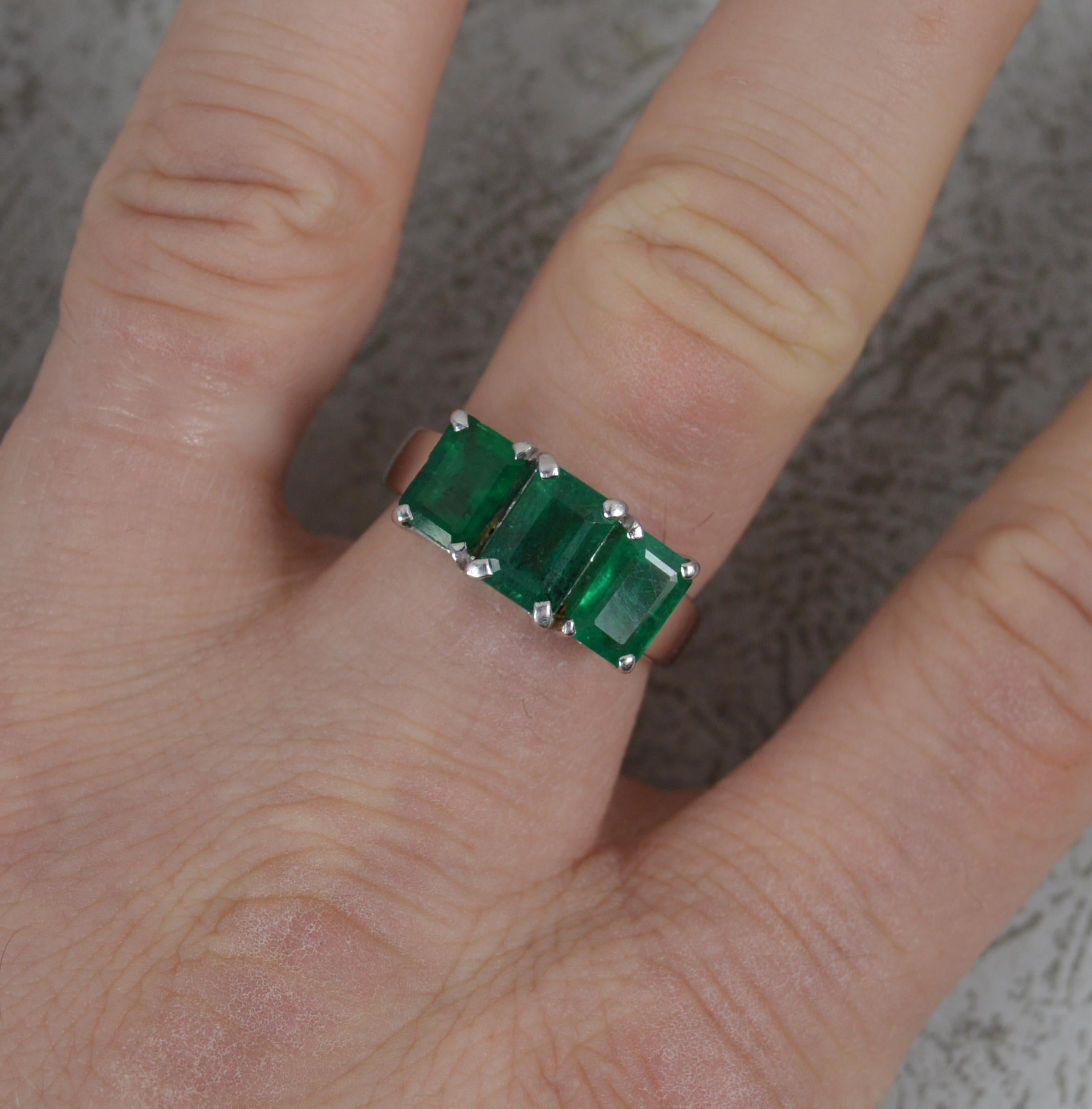 A superb Emerald trilogy ring.
Solid 18 carat white gold example.
Set with three large, emerald cut natural emerald stones in four claw settings.
16mm x 8mm, protruding 6.5mm off the finger.

CONDITION ; Very good. Clean band. Well set stones. Very