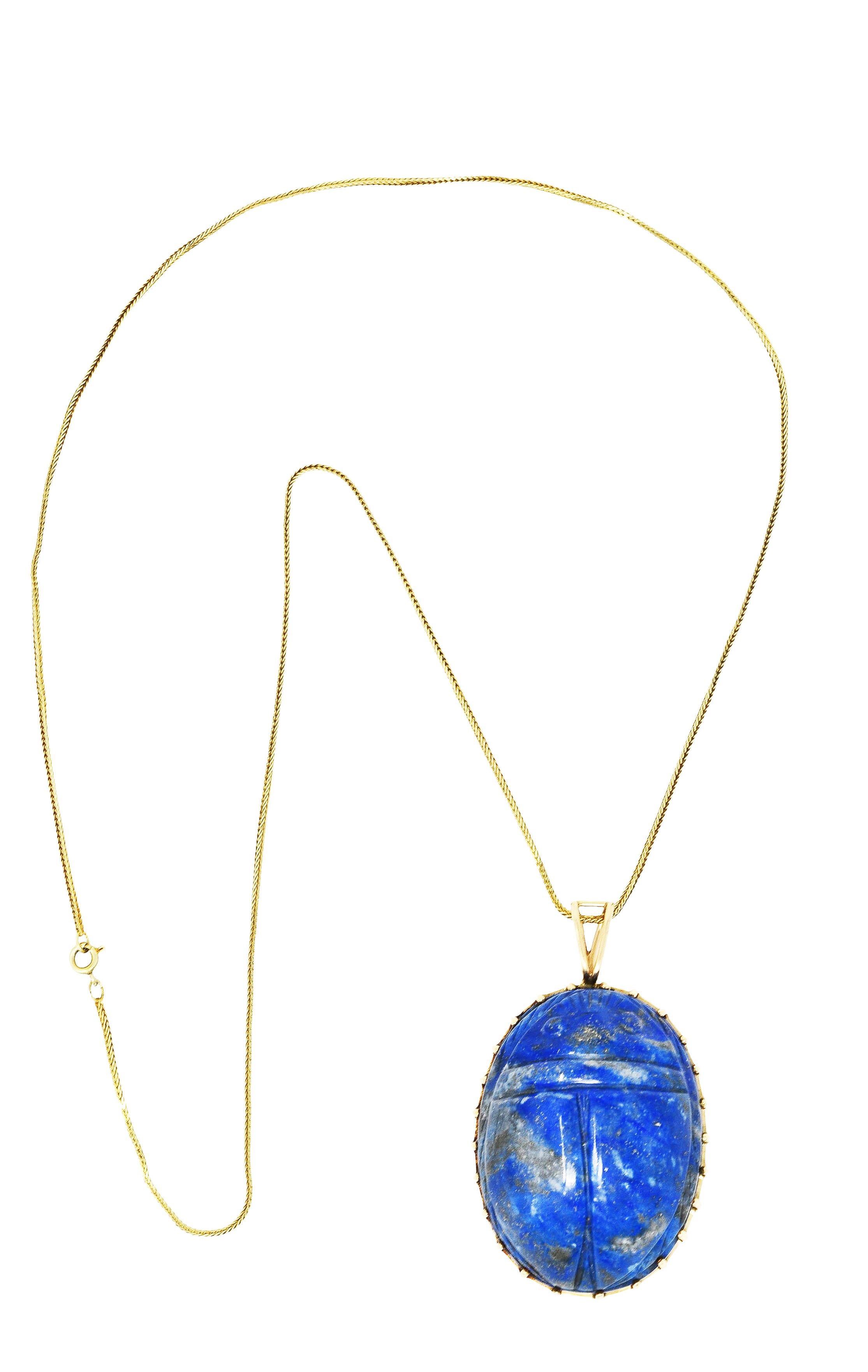 Necklace designed as gold box chain suspending lapis lazuli scarab pendant

Scarab beetle carving features grooved back and ridged legs

Lapis is opaque ultramarine blue with strong light to dark grey mottling and pyrite flecks

Set in arching high