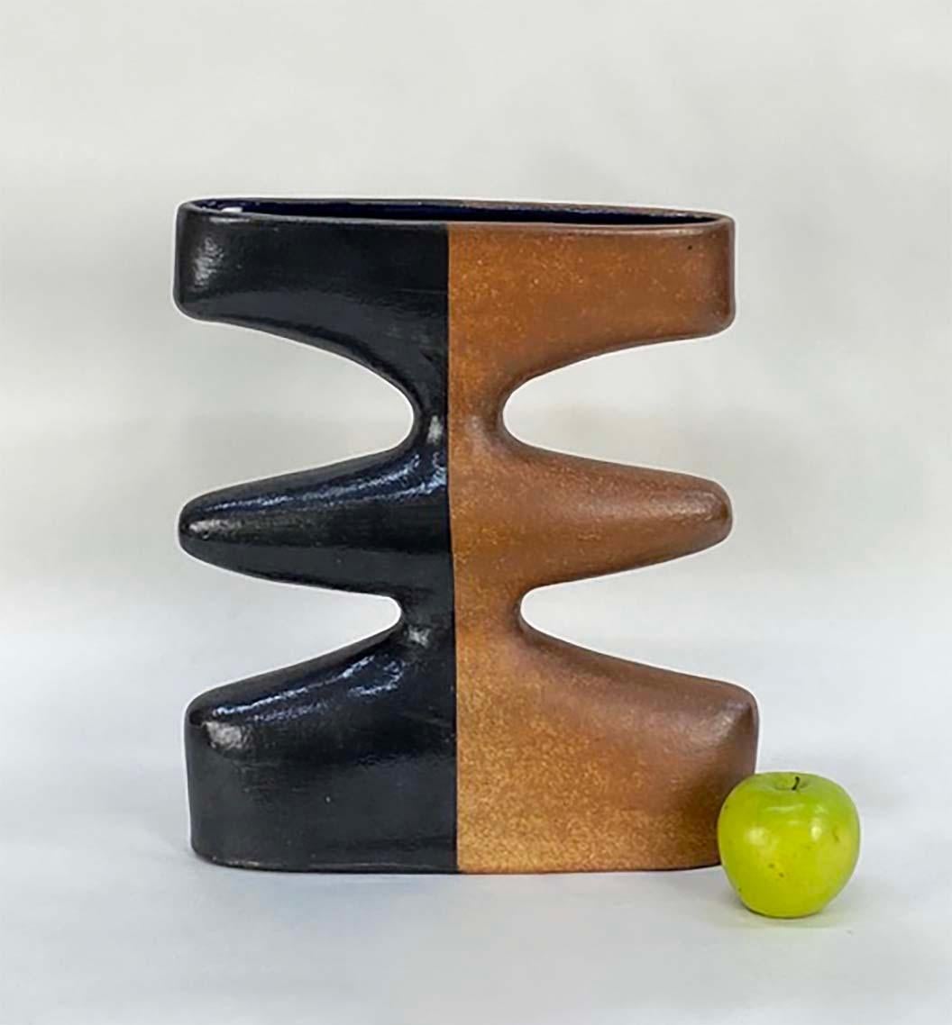 Here's a highly unusual hand-built pottery vase from the 1970s. The very sculptural shape is glazed half clear--letting the natural terracotta clay color come through--and half black. The result is a very striking modernist vase that's functional