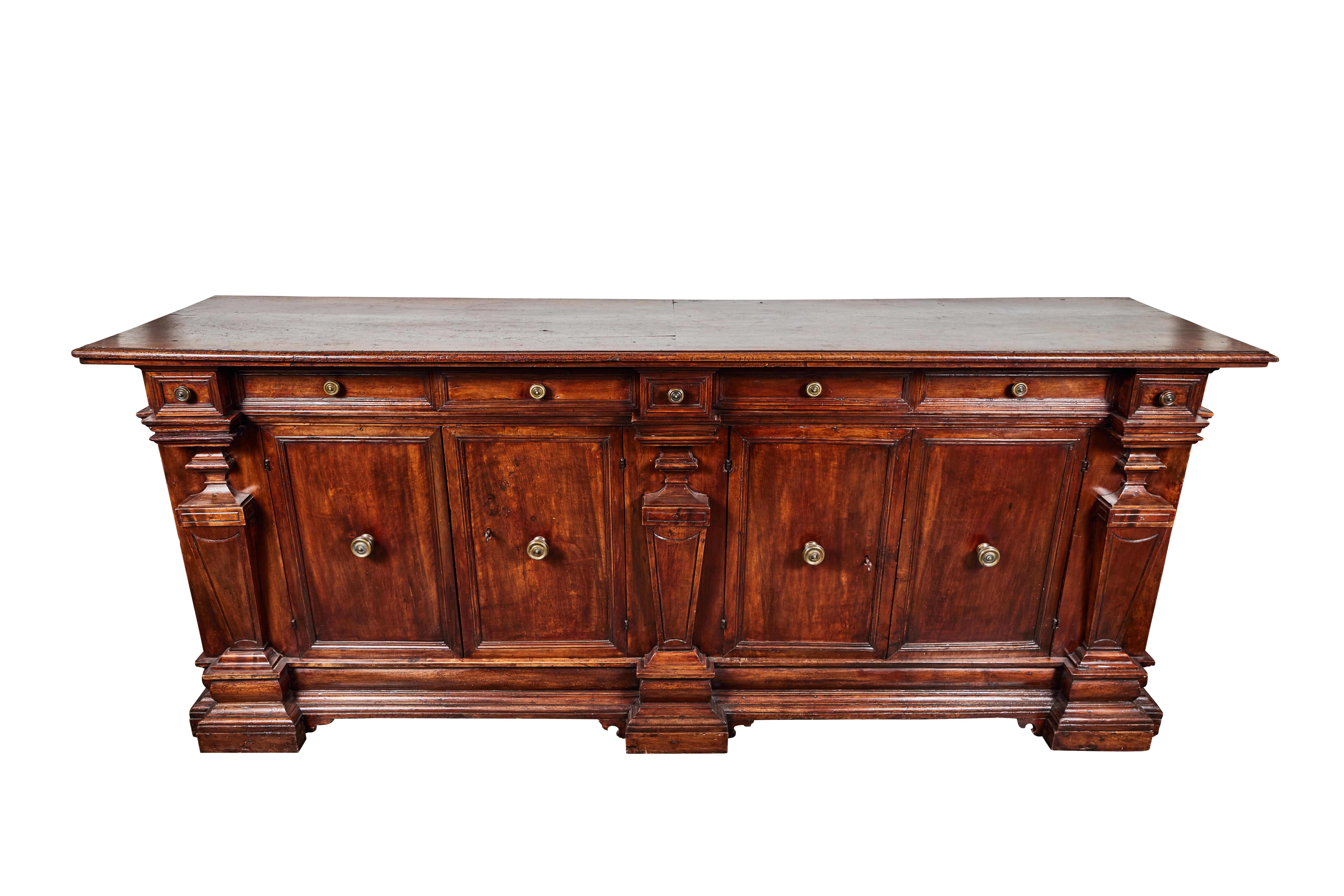 A huge, beautifully carved, circa 1800 solid walnut seven-drawer, four-door Tuscan buffet featuring paneled woodwork, and a series of faux pilasters along the facade. The piece retaining it's original, gilt bronze hardware.
