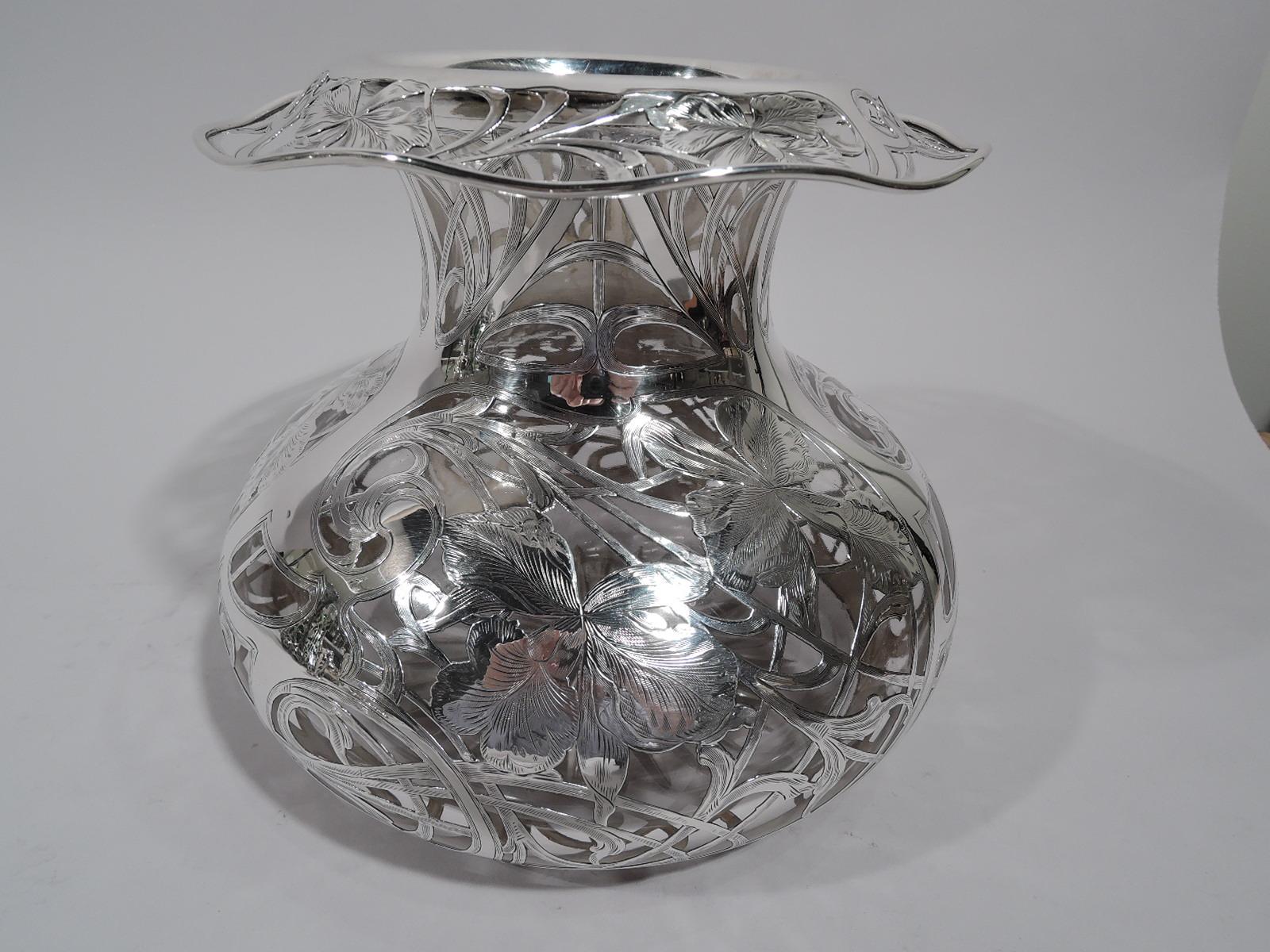 Turn of the century Art Nouveau glass vase with engraved silver overlay. Bellied bowl with short neck and open and wavy turned-down rim. Overlay in form of loose flower heads and entwined and whiplash tendrils. Rim ornament same. Dense and dramatic.