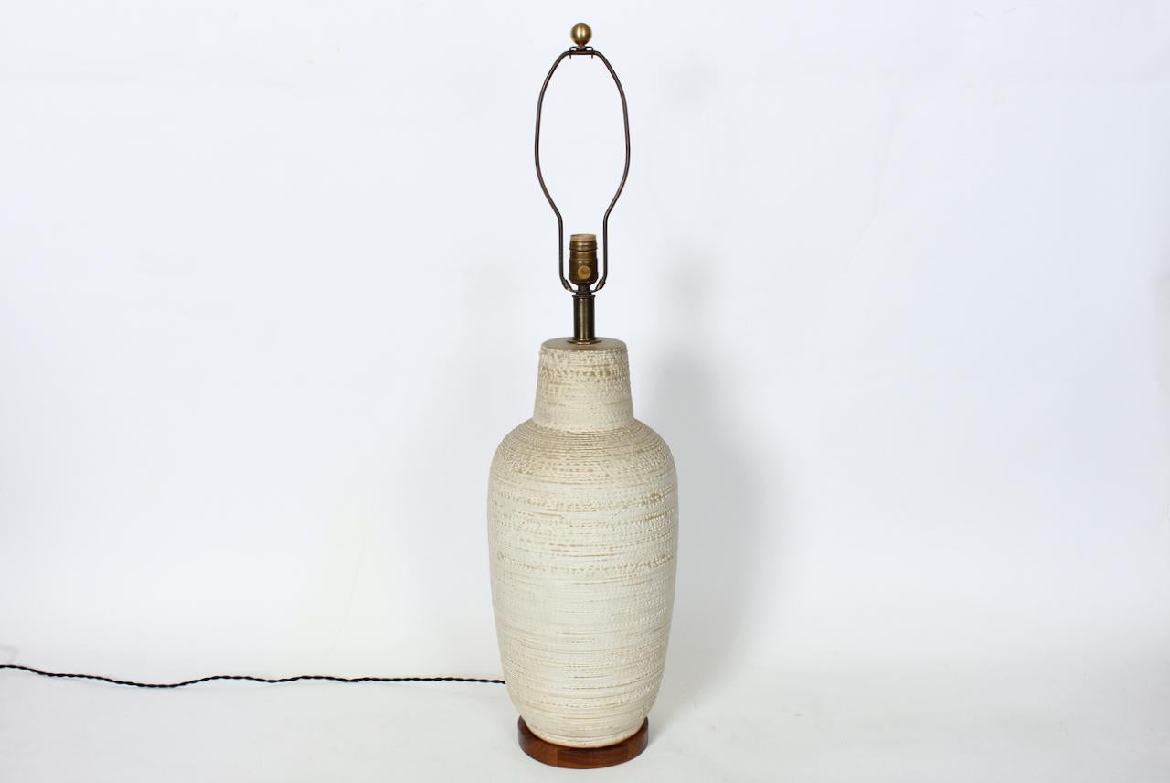Grande lampe de table classique Design/One en poterie texturée à glaçure crème. Whiting, la forme classique de la bouteille fabriquée à la main par Design/One est ornée d'une bande horizontale en blanc cassé et d'une glaçure crème claire. Patine