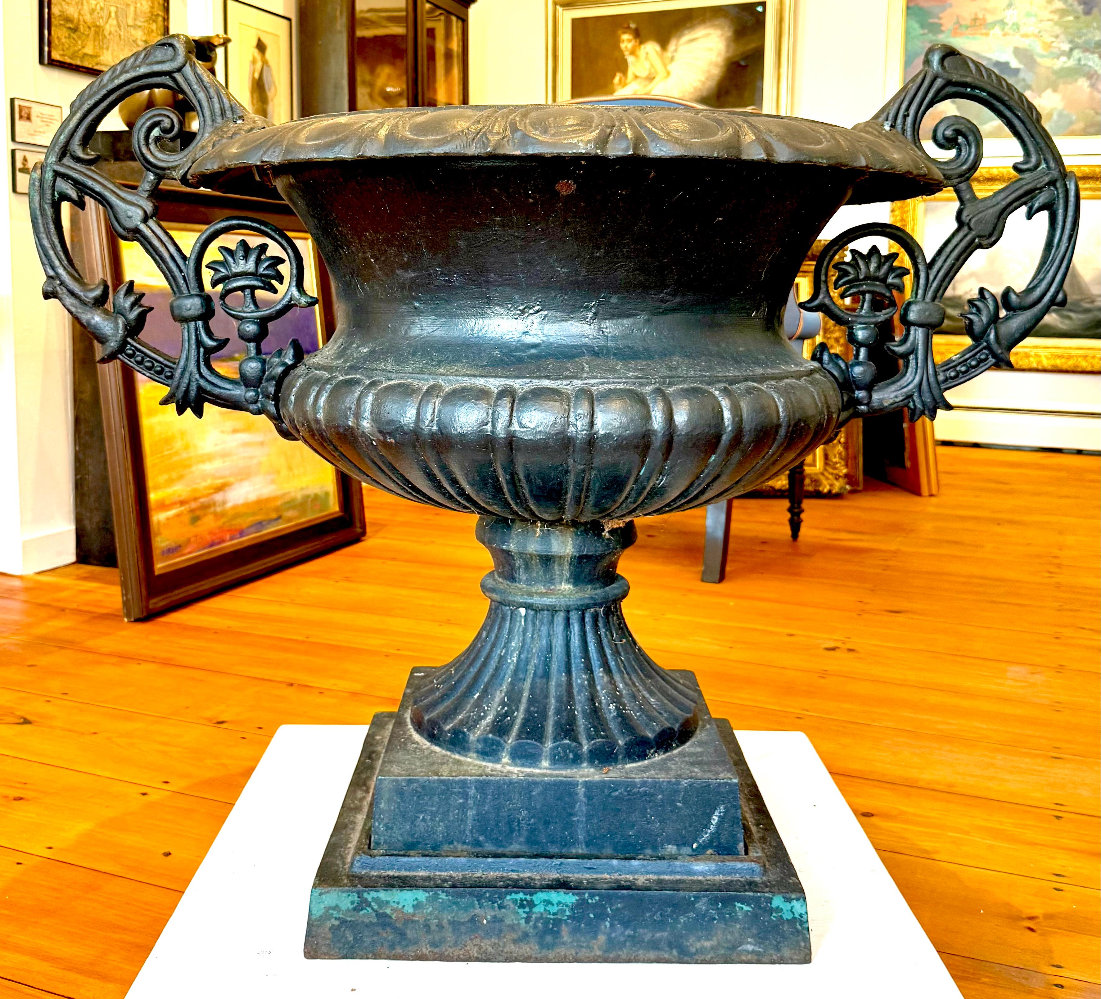 Monumental cast iron urn with interesting handle design.  Old black over older green paint.  Dates to the early 20th century and came out of a grand estate in New England.  Measures 32