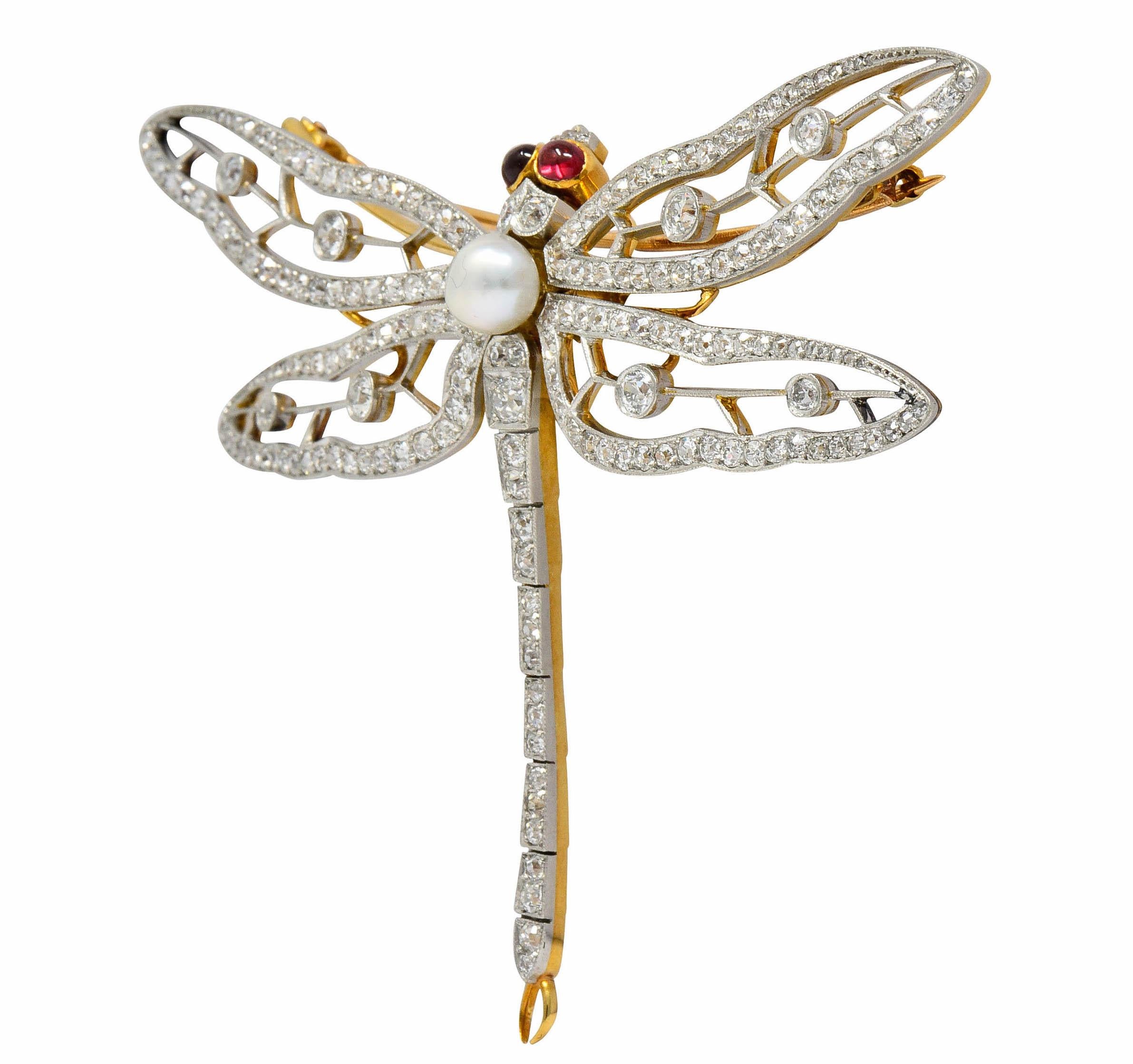 Designed as a large dragonfly with delicately pierced wings accented by milgrain

With oval spinel cabochon eyes, bezel set in gold, well-matched and light red in color

Centering a 6.5 mm semi-round button pearl, white in body color with silvery