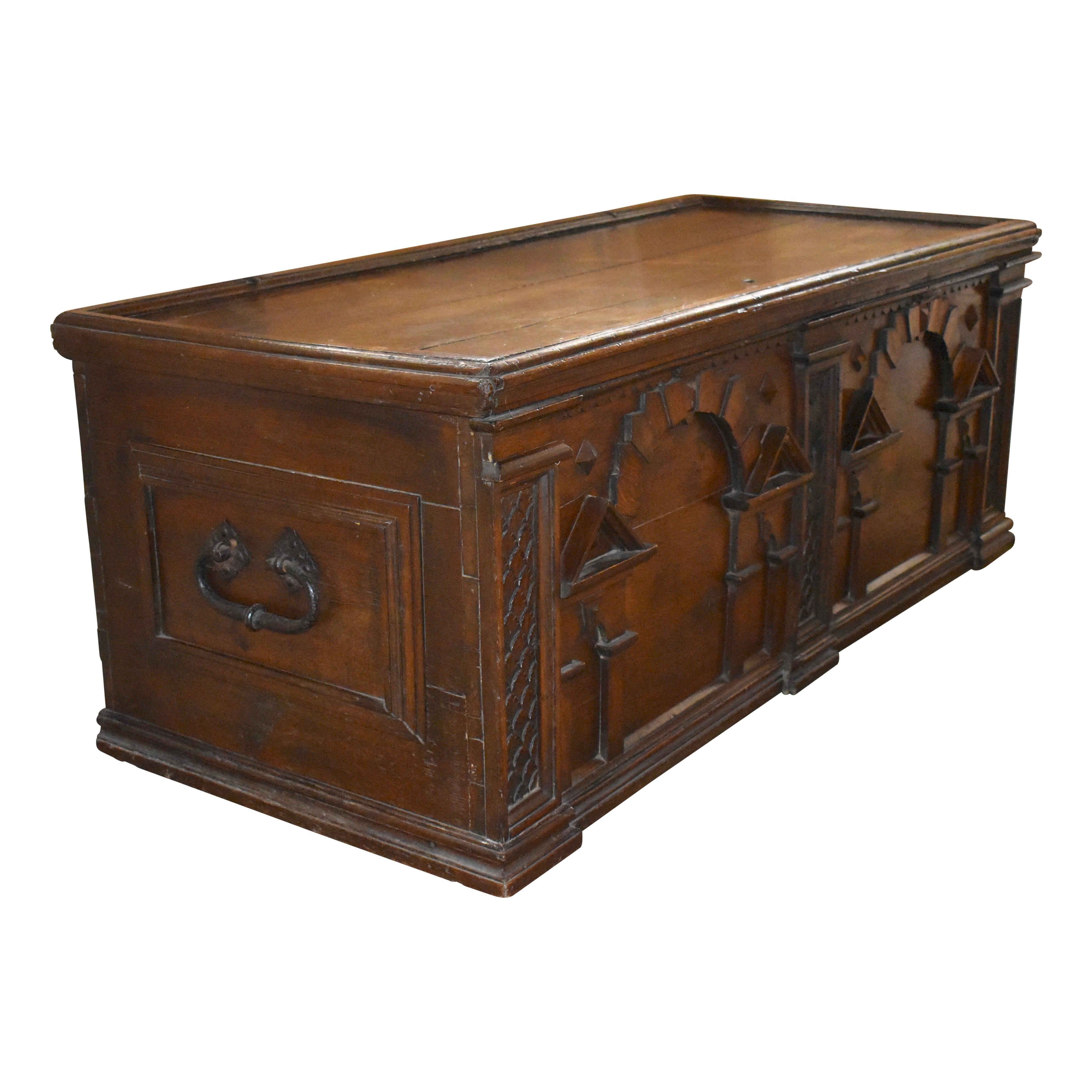 Crafted from European pine at the turn of the century, this substantial trunk features two beautifully designed 
recessed front panels flanked by three carved pieces, hand forged iron handles, and long iron hinges. The top lifts to generous