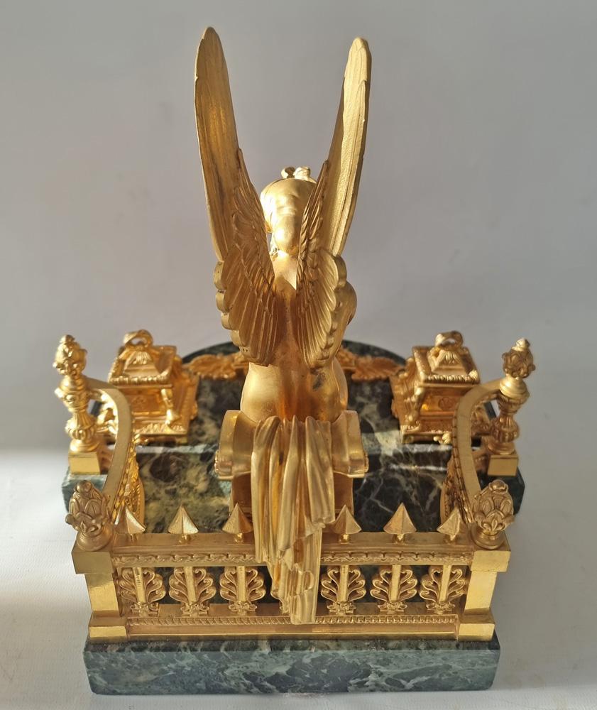 Encrier en marbre vert et bronze doré de la fin de l'Empire français. Déesse ailée de la victoire extrêmement bien moulée, assise sur une chaise klismos de style classique, penchée sur un autel en feu. Deux encriers se trouvent à l'avant et sur les