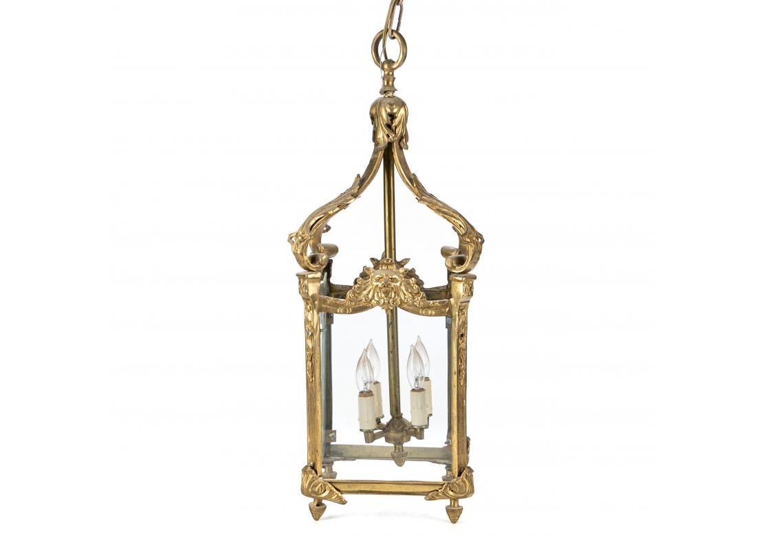 Antique style brass finished 4 light etched glass lantern featuring lion head embellishments, acanthus leaf and scroll motif with acorn finials at corners and on central column. Floral and foliate etched glass panels. Chain drop.
Measures: 9