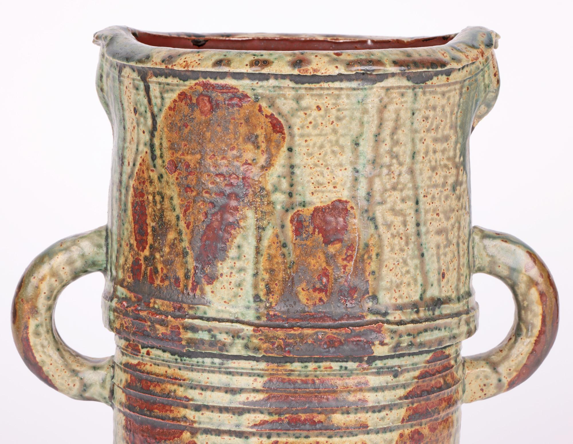 A very large and impressive twin handled studio pottery vase with a streaked and salt glazed finish probably dating from the 20th century. The vase stands on a wide round unglazed foot and is of tall cylindrical shape with horizontal incised linear