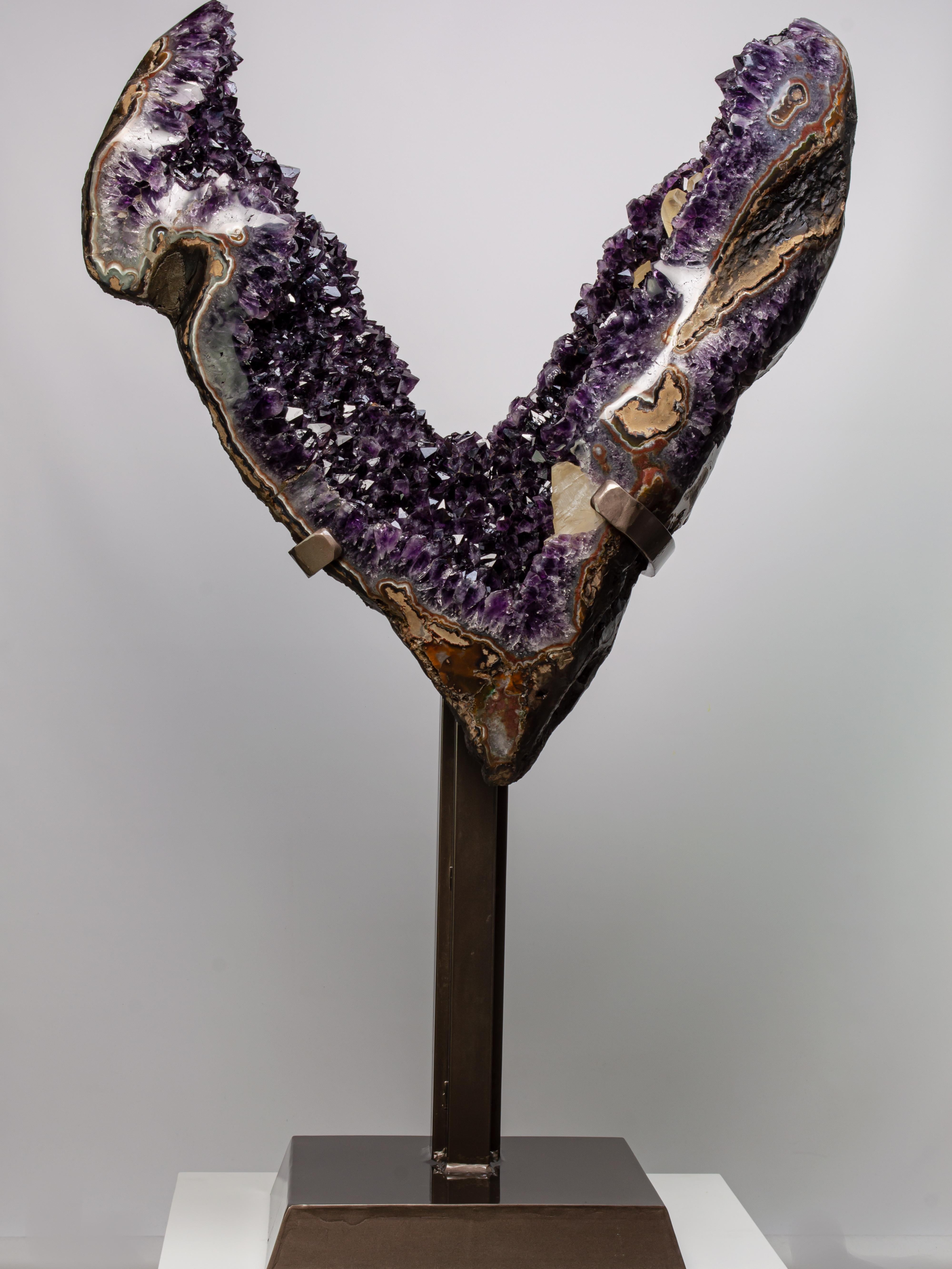 This very large and impressive formation preserves amethyst of very high peaks
and deep colour, punctuated by multiple cream coloured calcites. Playing beautifully in the light, the borders of this natural sculpture have been sympathetically
