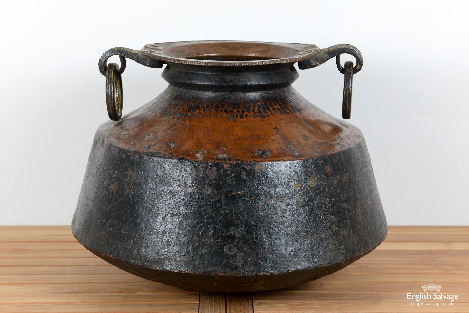 Large hammered copper pot with two ring handles and a patinated finish. The pot was reclaimed from India and is in a solid condition with some knocks from past use.