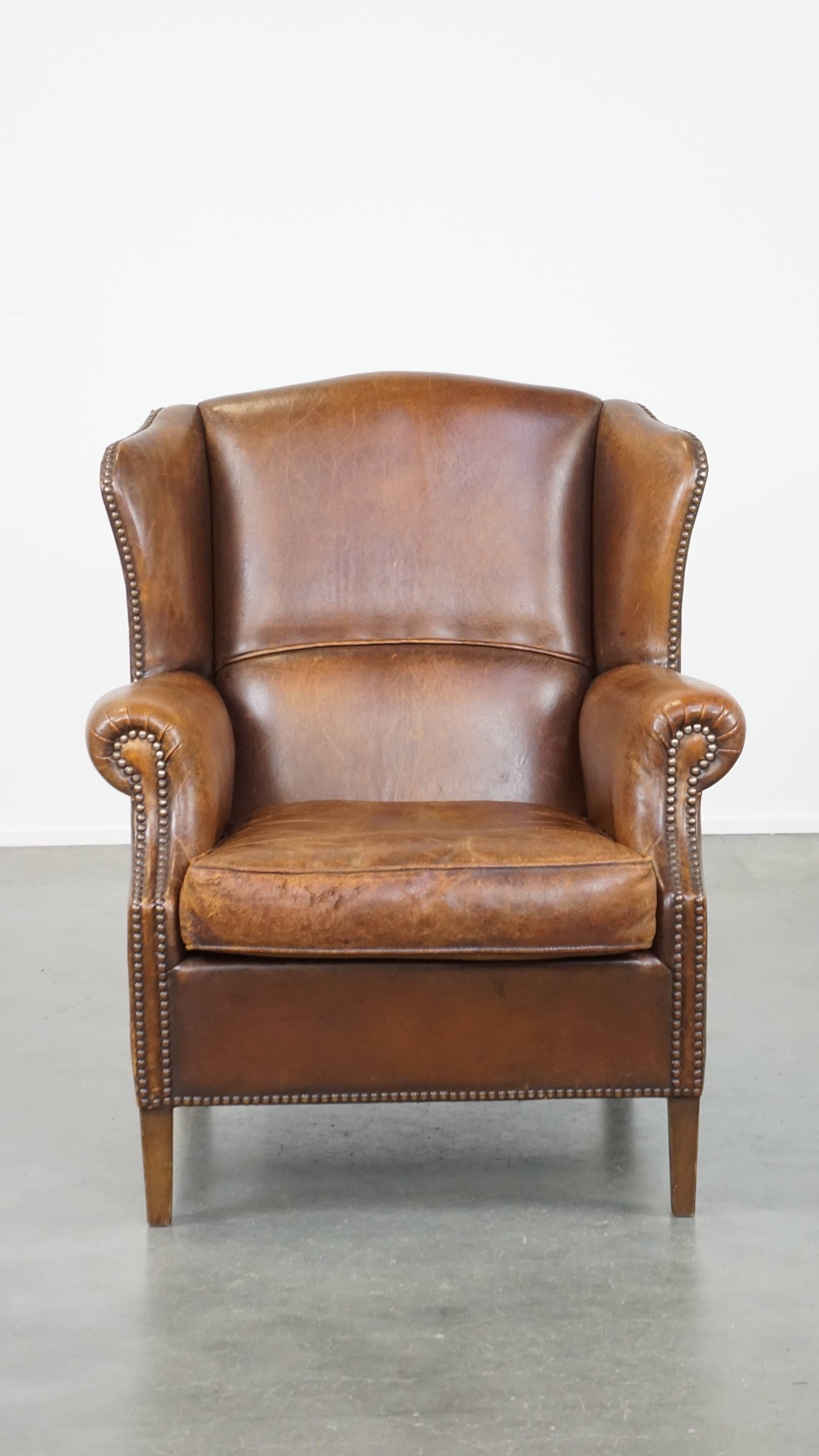 Ce subtil fauteuil à oreilles en peau de mouton est le complément idéal pour l'amateur de charme anglais intemporel. Il peut facilement être placé dans presque tous les intérieurs. Cette chaise à oreilles a une belle couleur cognac et est finie avec